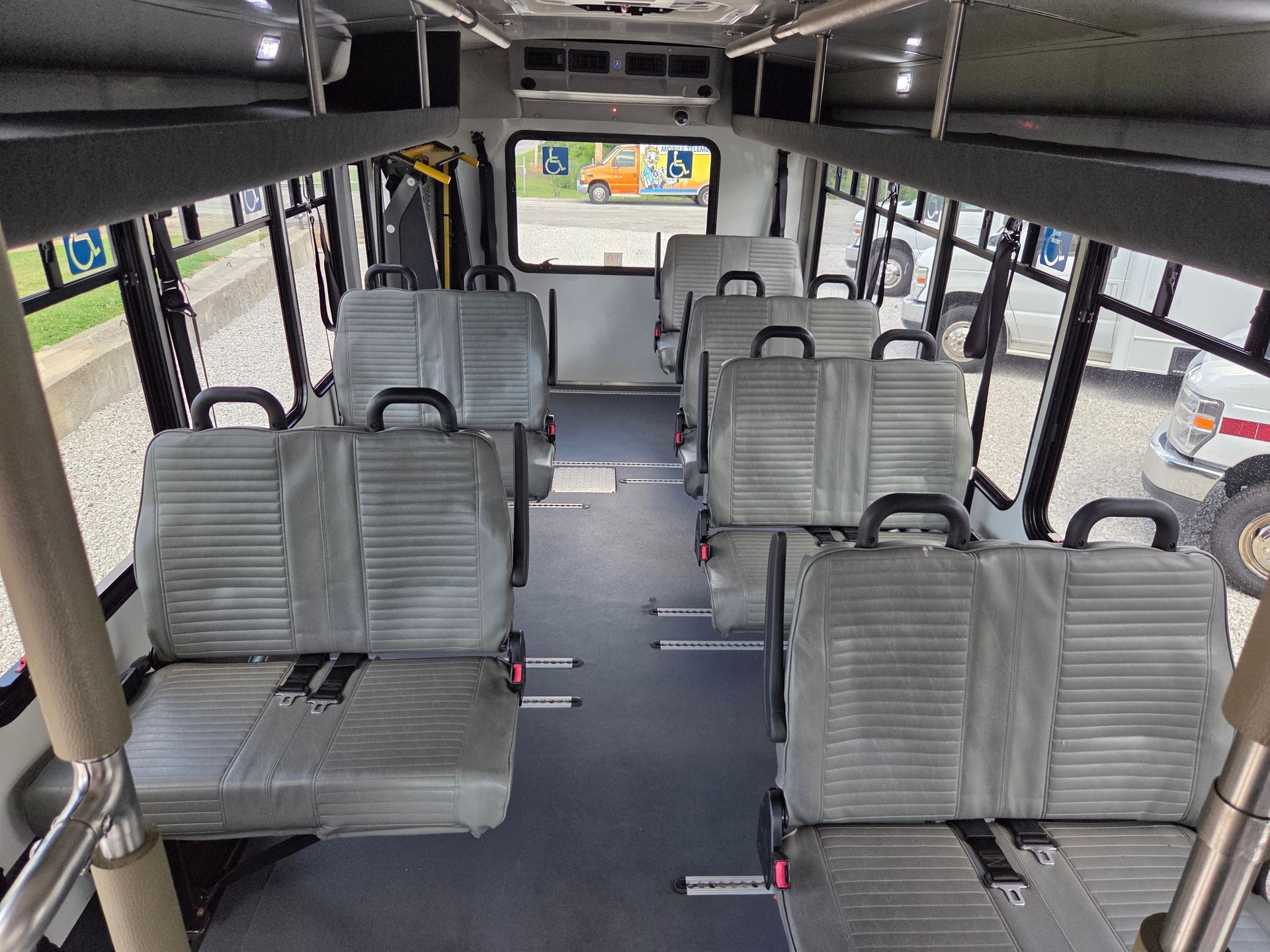 Empty bus interior with gray seats and a small TV screen at the front