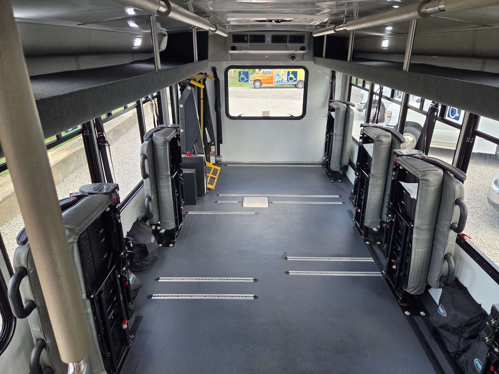 Empty bus interior with folded seats and wide center aisle, viewed toward the rear window