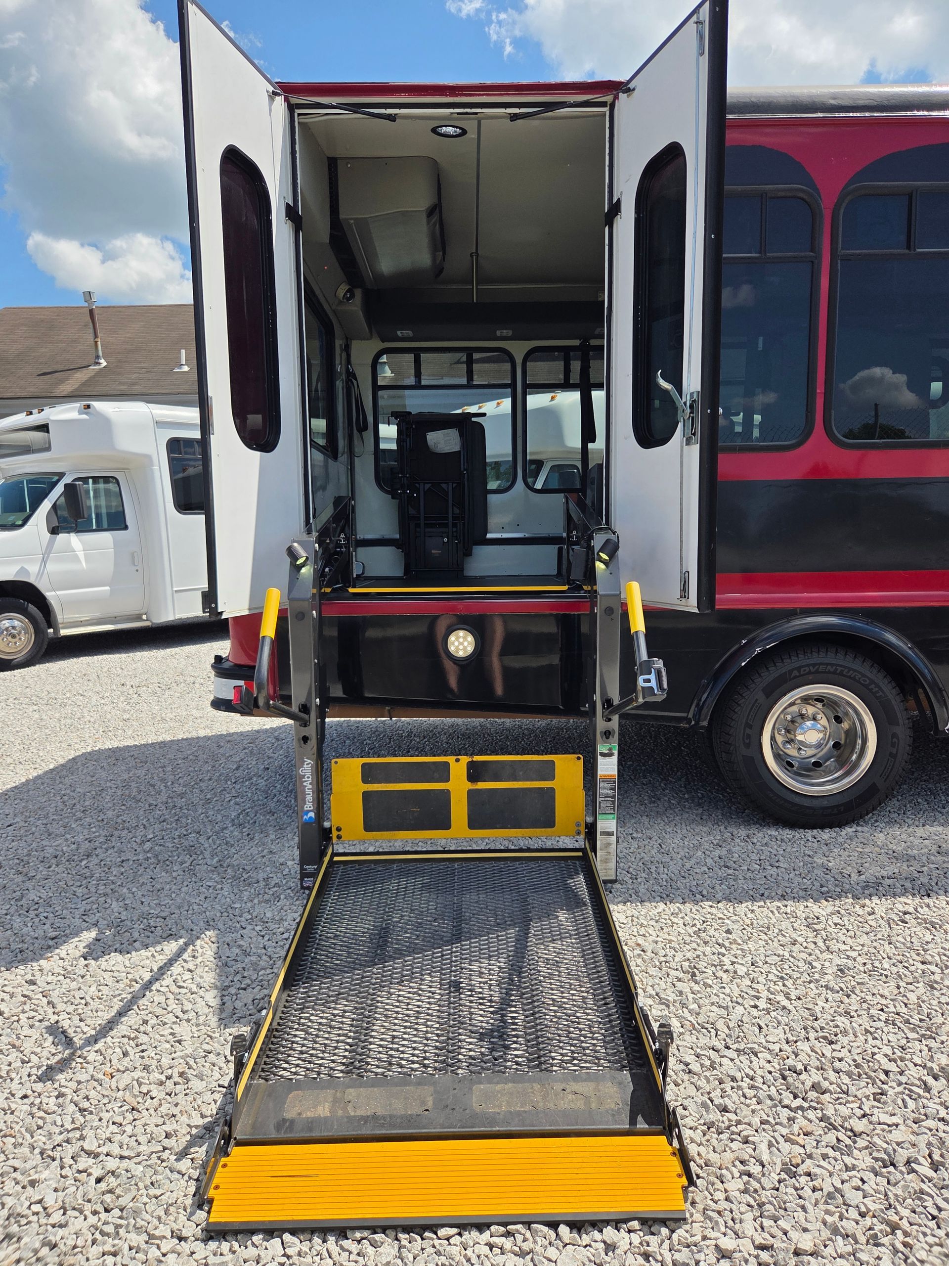 Wheelchair lift extended from an open van, showing a yellow ramp and interior seating.