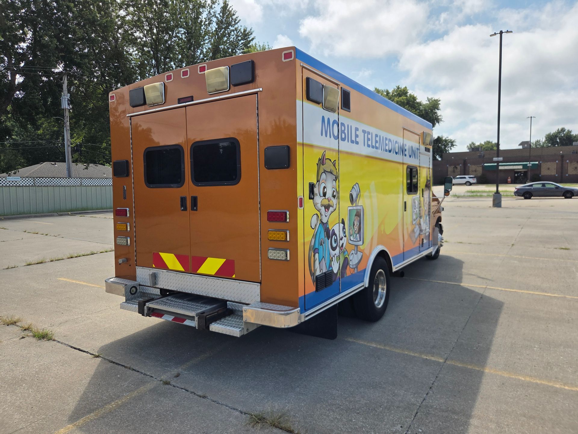 Orange mobile classroom truck parked in a lot, with colorful educational graphics on the side.