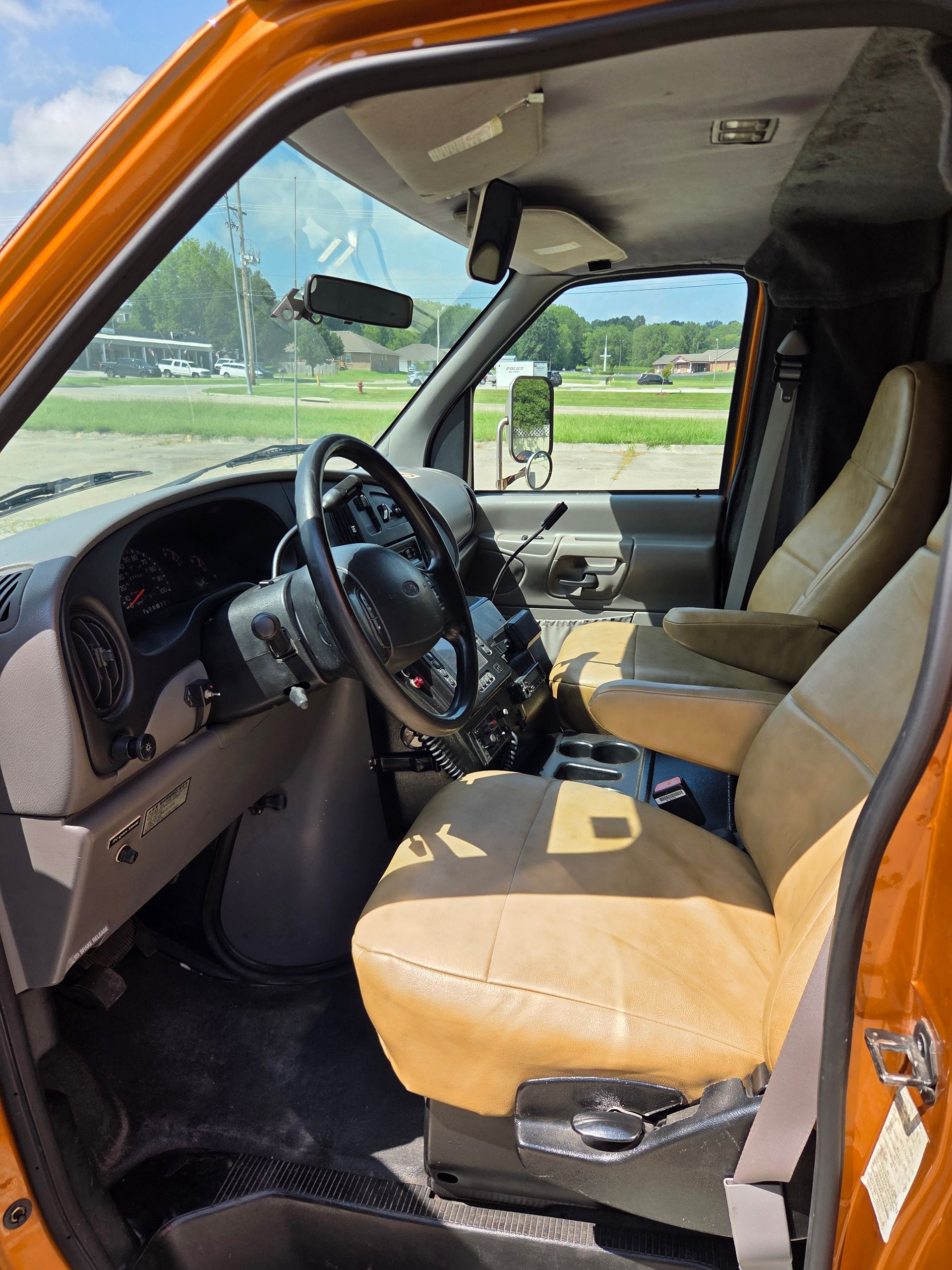 Orange truck interior with tan seats and steering wheel, viewed through the open driver’s door
