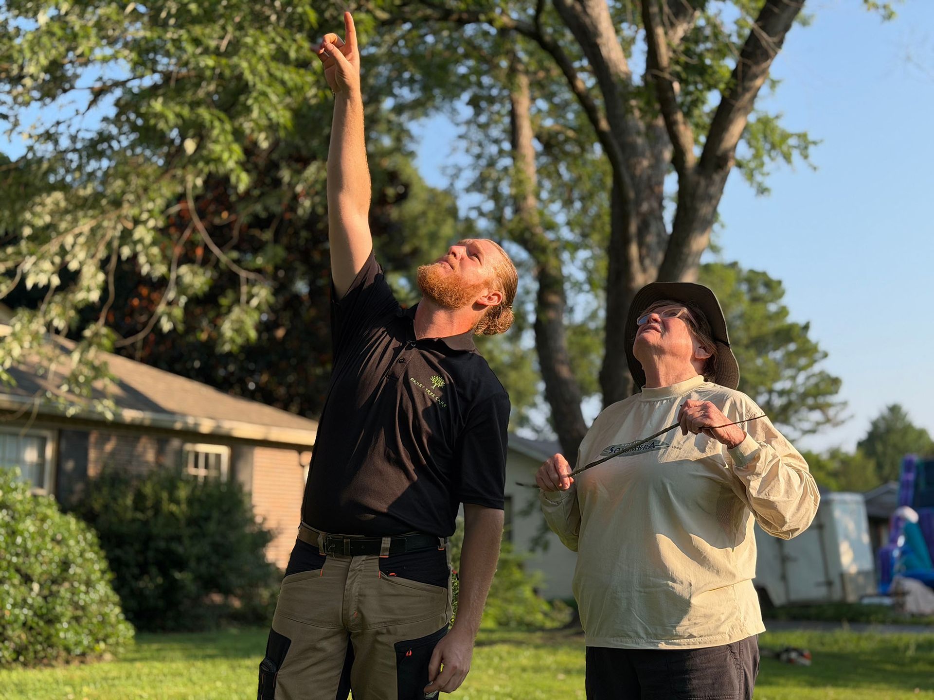 Two people outdoors, one reaching up toward the sky while the other looks on beside him.