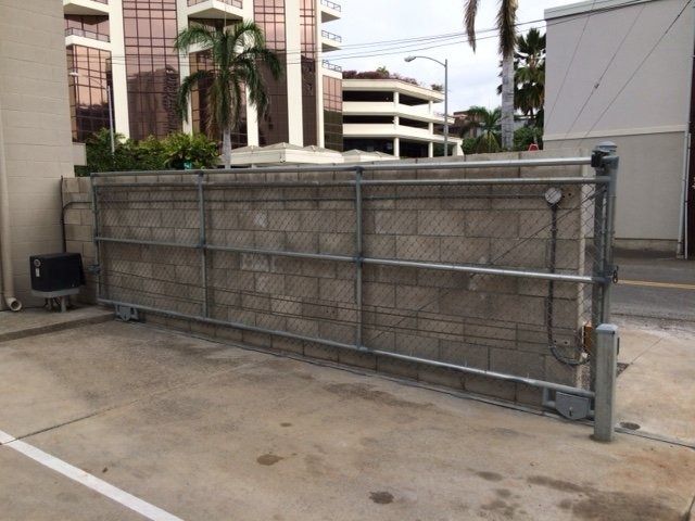 Sliding metal gate along a concrete block wall in an urban setting.