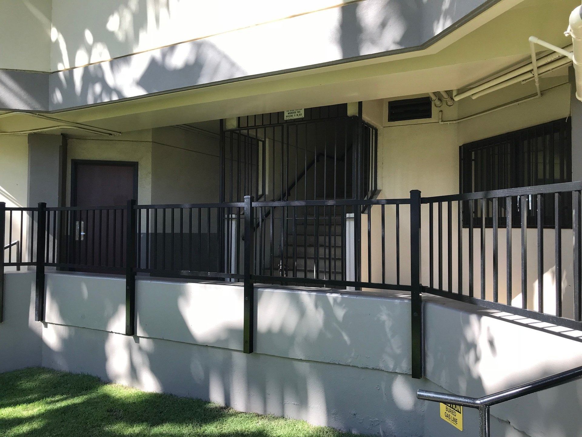 Exterior of a building with a black metal ramp, railings, and windows.