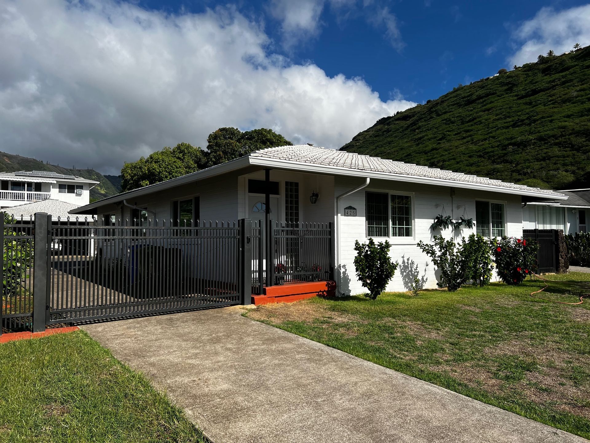 White house with dark fence and mountain background.