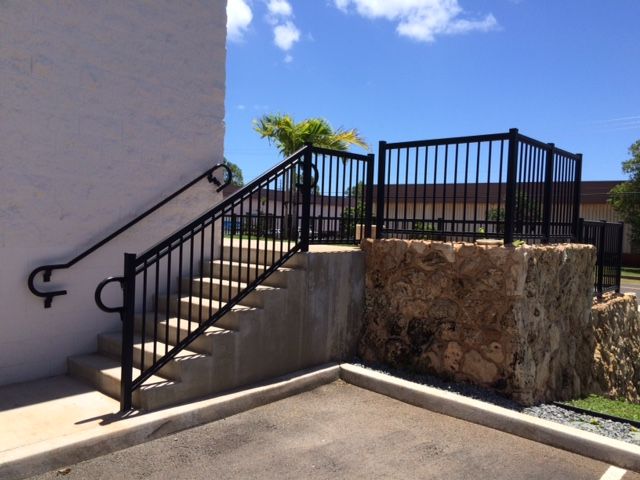 Black metal handrails and fence on outdoor concrete stairs and stone wall.