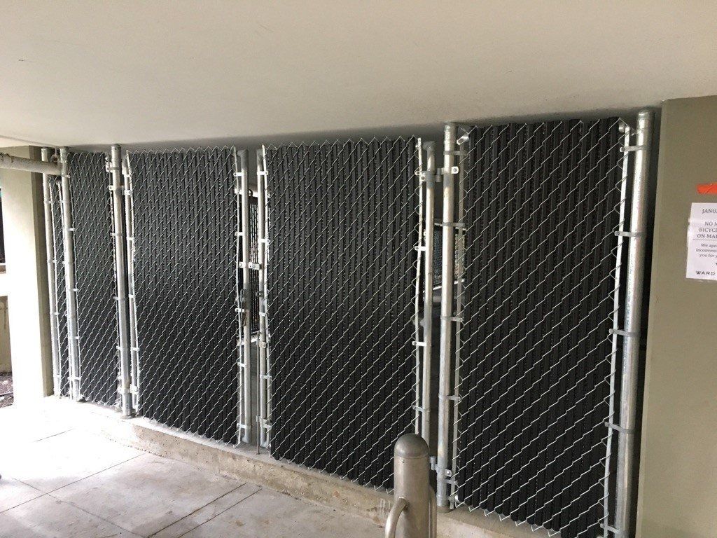 Black privacy slats in a chain-link fence, under a concrete overhang.