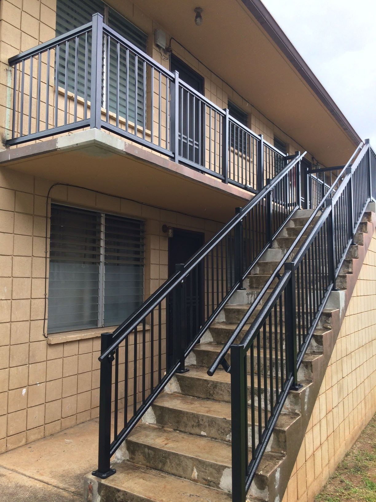 Exterior view of a building with a staircase and a balcony, both with black metal railings.