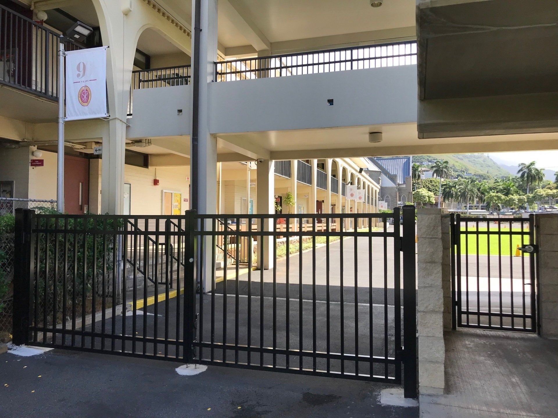 Black metal gate and fence in front of a building with a white exterior.