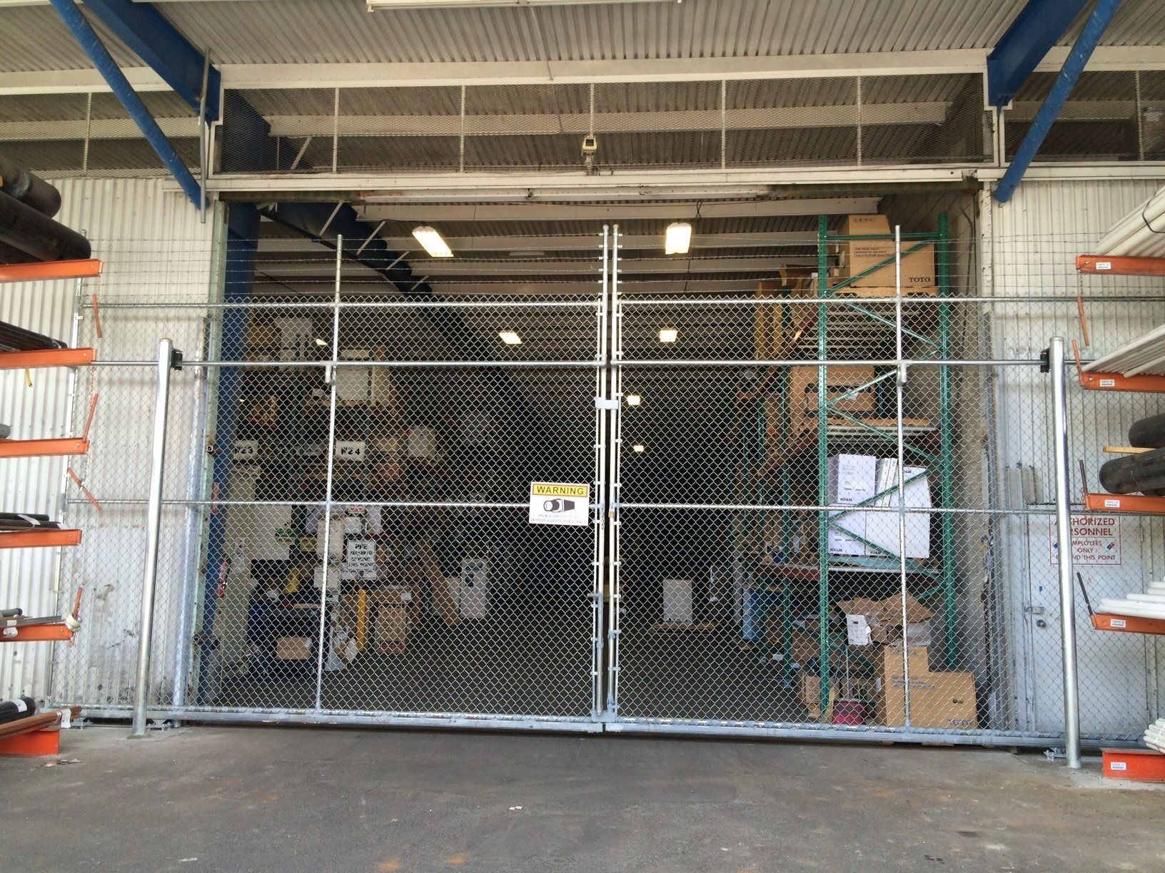 Chain link gate in front of a warehouse opening, shelves visible inside.