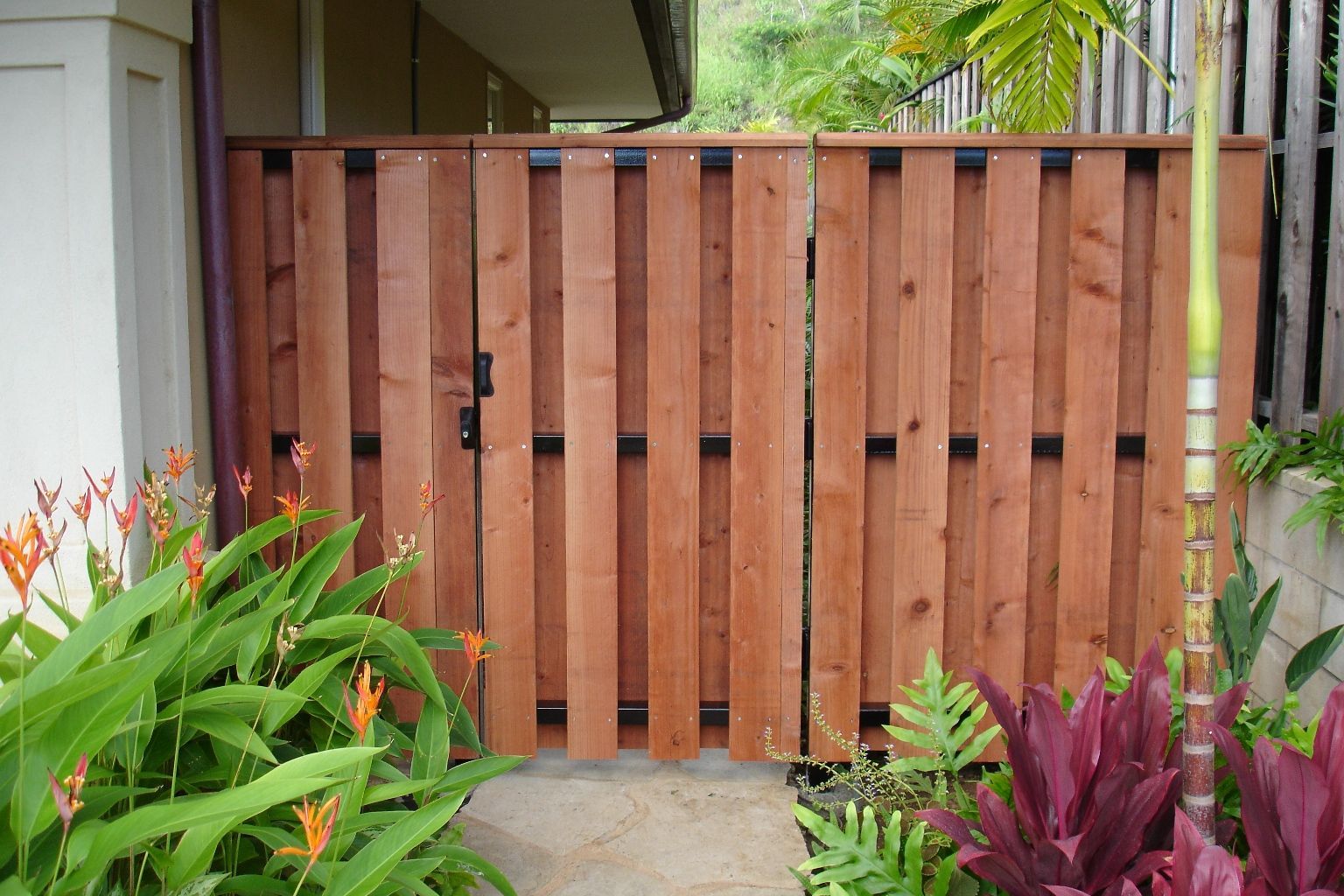 Wooden gate with vertical slats, brown color, in a garden.
