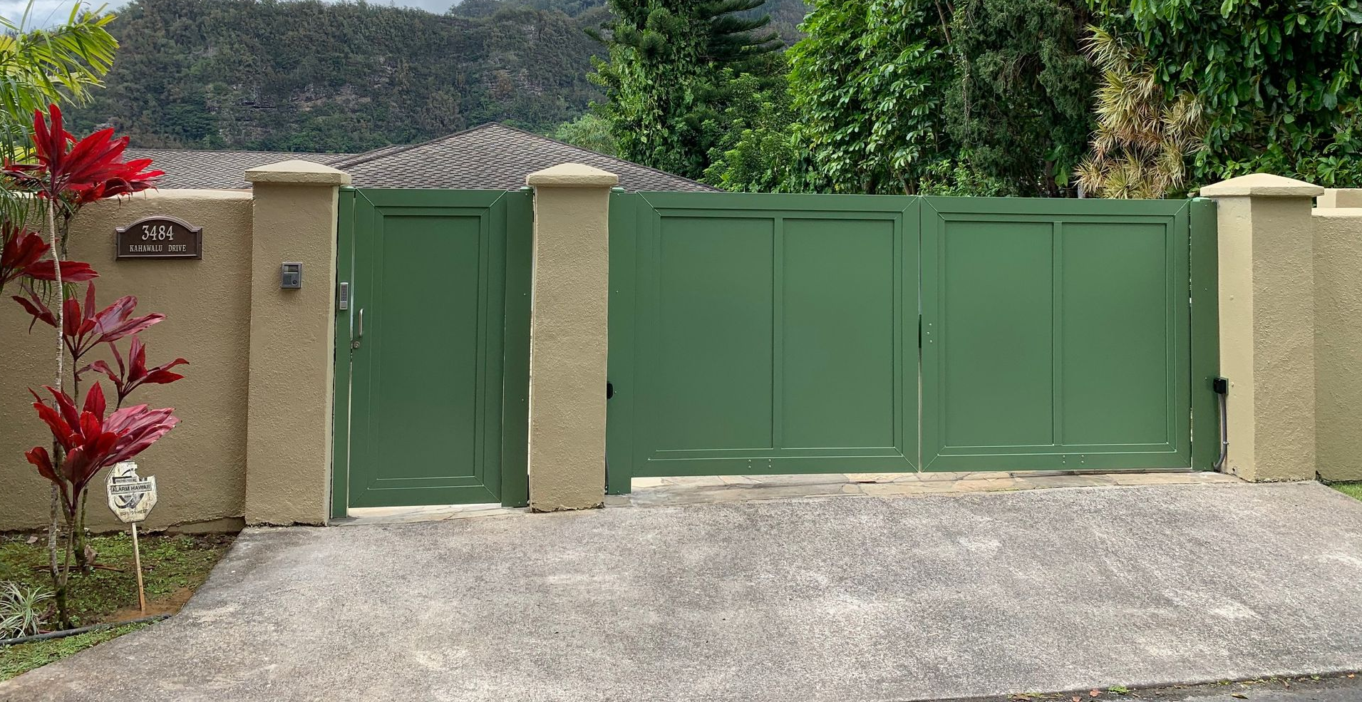 White vinyl fence in a yard with grass, rocks, and houses in the background.