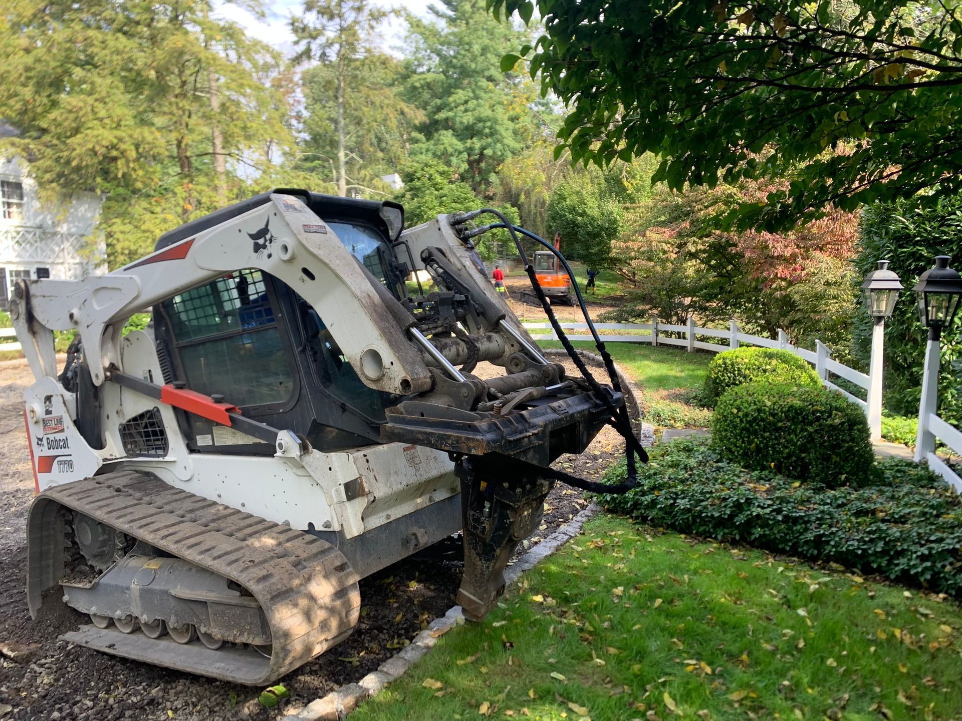 A bobcat is digging a hole in a yard.