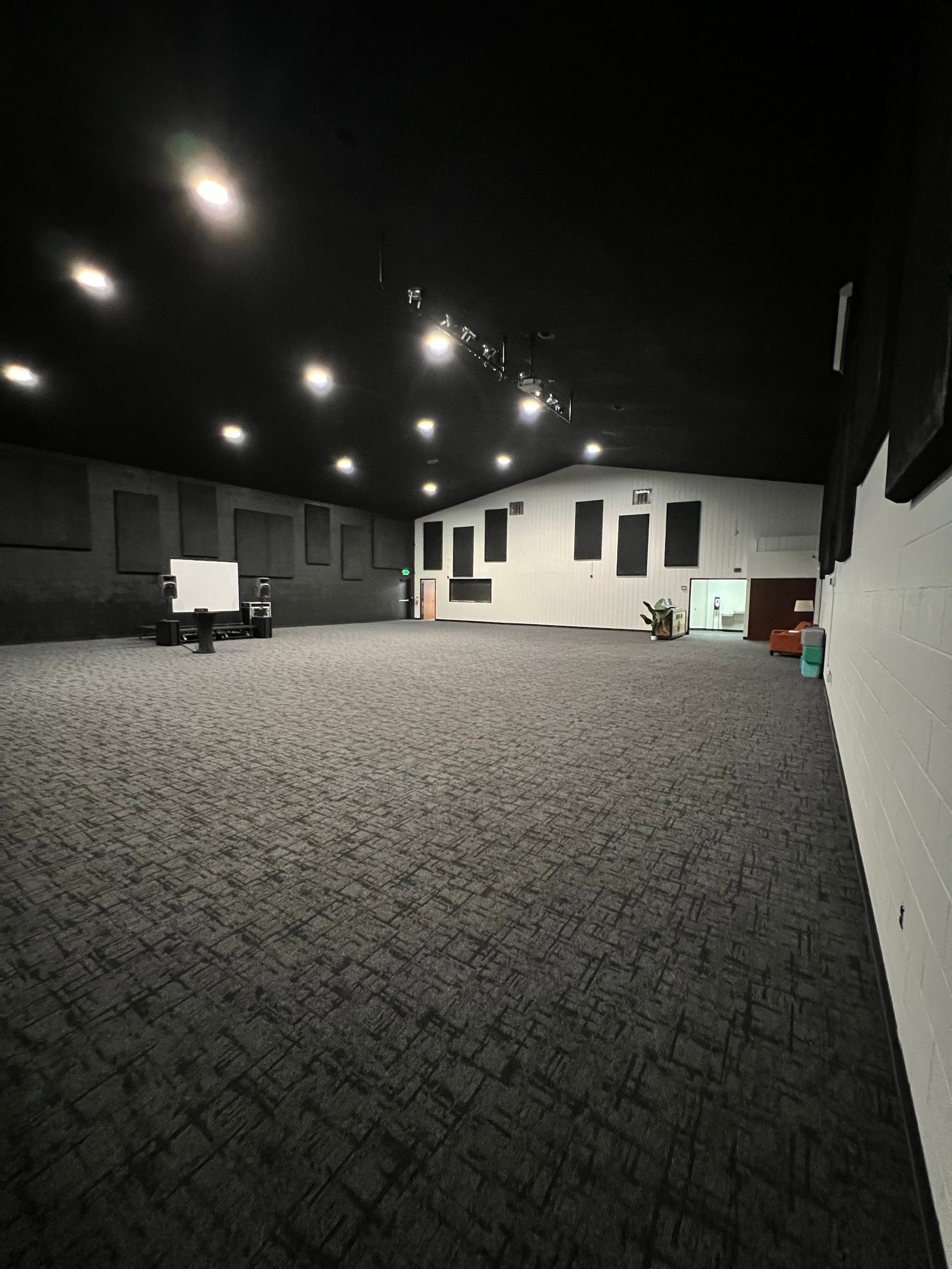 Empty indoor event hall with patterned carpet, white walls, and ceiling spotlights