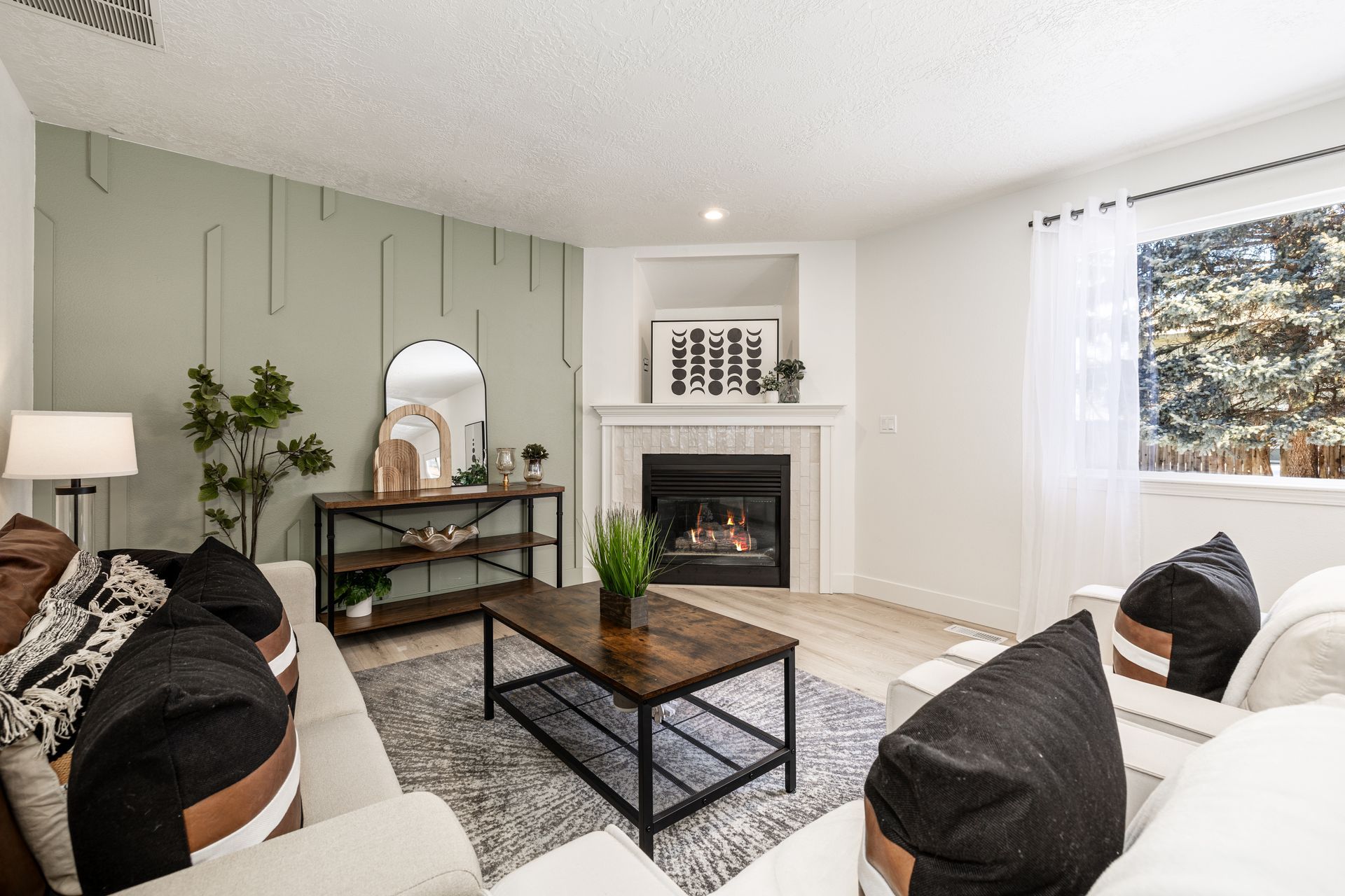 Bright living room with white sofas, fireplace, coffee table, and green accent wall