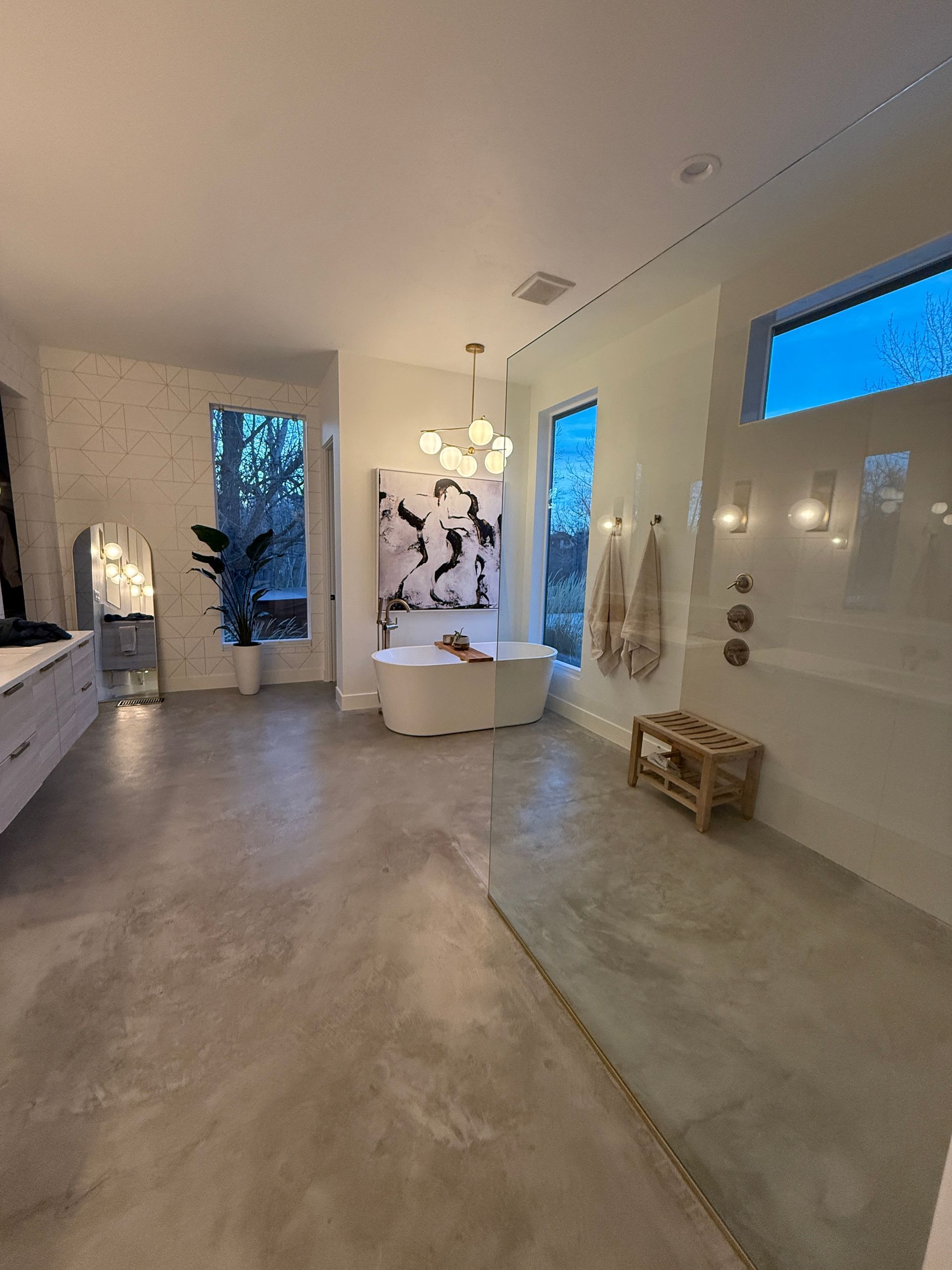 Modern white hallway with glossy floor, blue-lit windows, wall art, and a small bench.