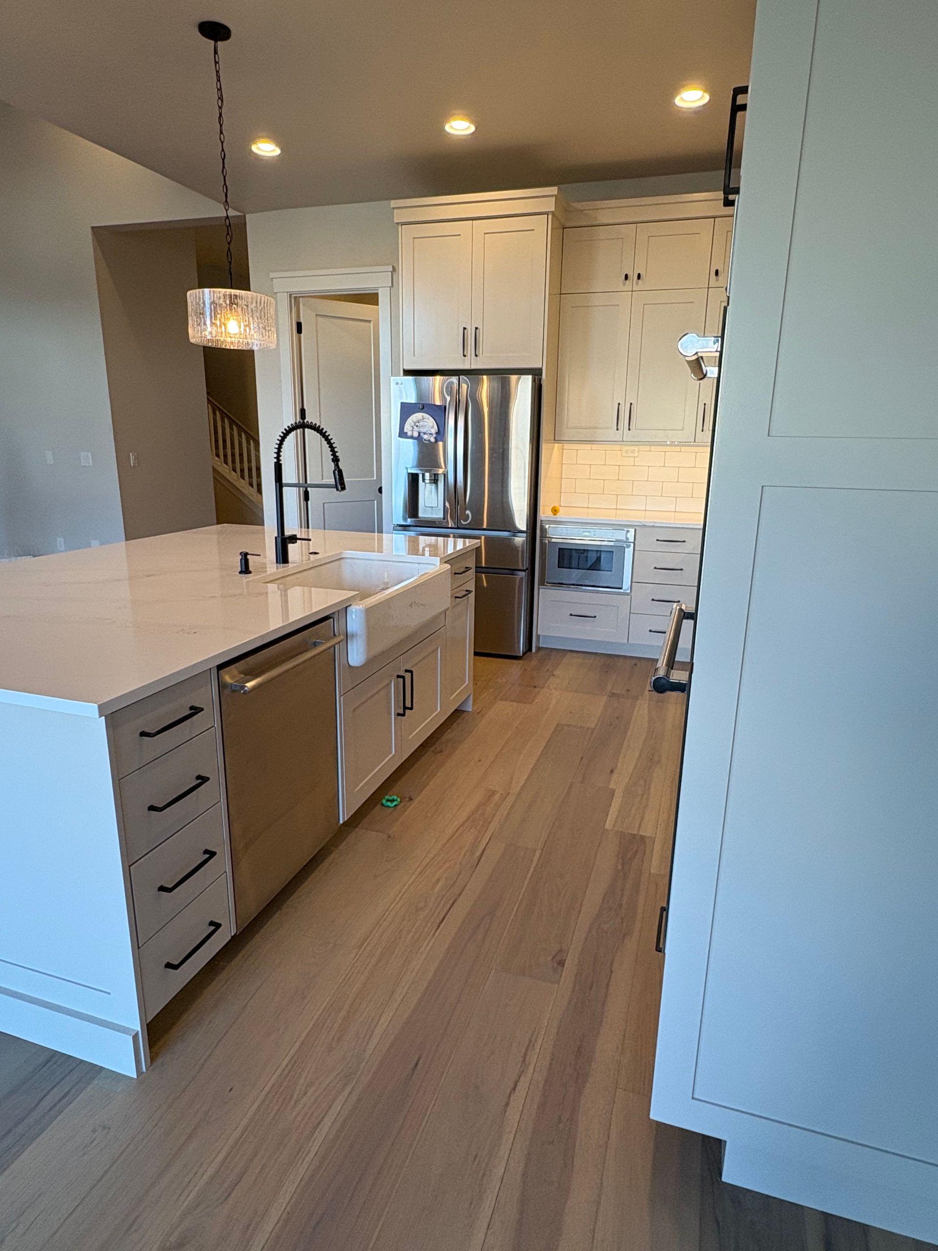 Modern white kitchen with island, stainless steel appliances, and light wood floors