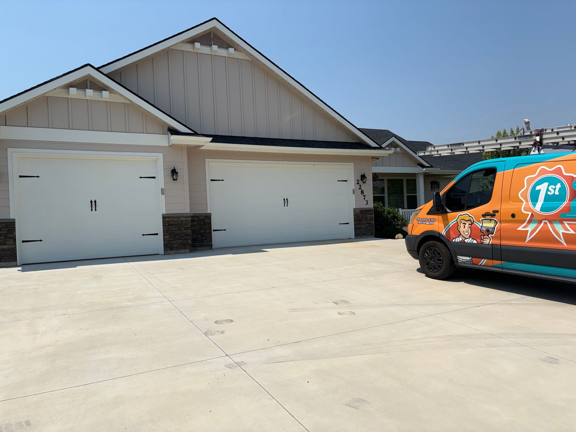 Suburban two-car garage with white doors and a brightly wrapped service van parked in the driveway
