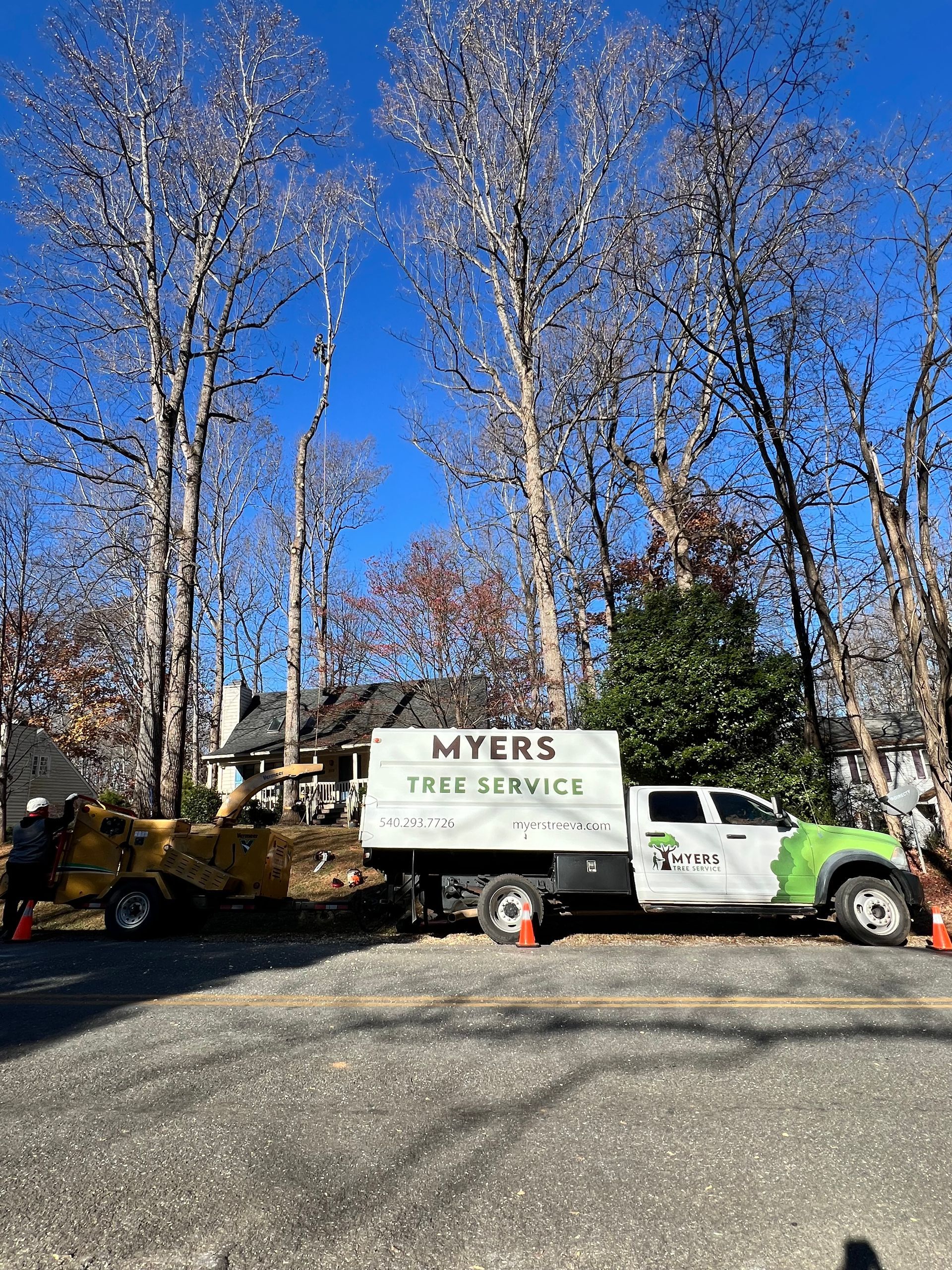 A truck is parked in a parking lot next to a tree stump grinder.