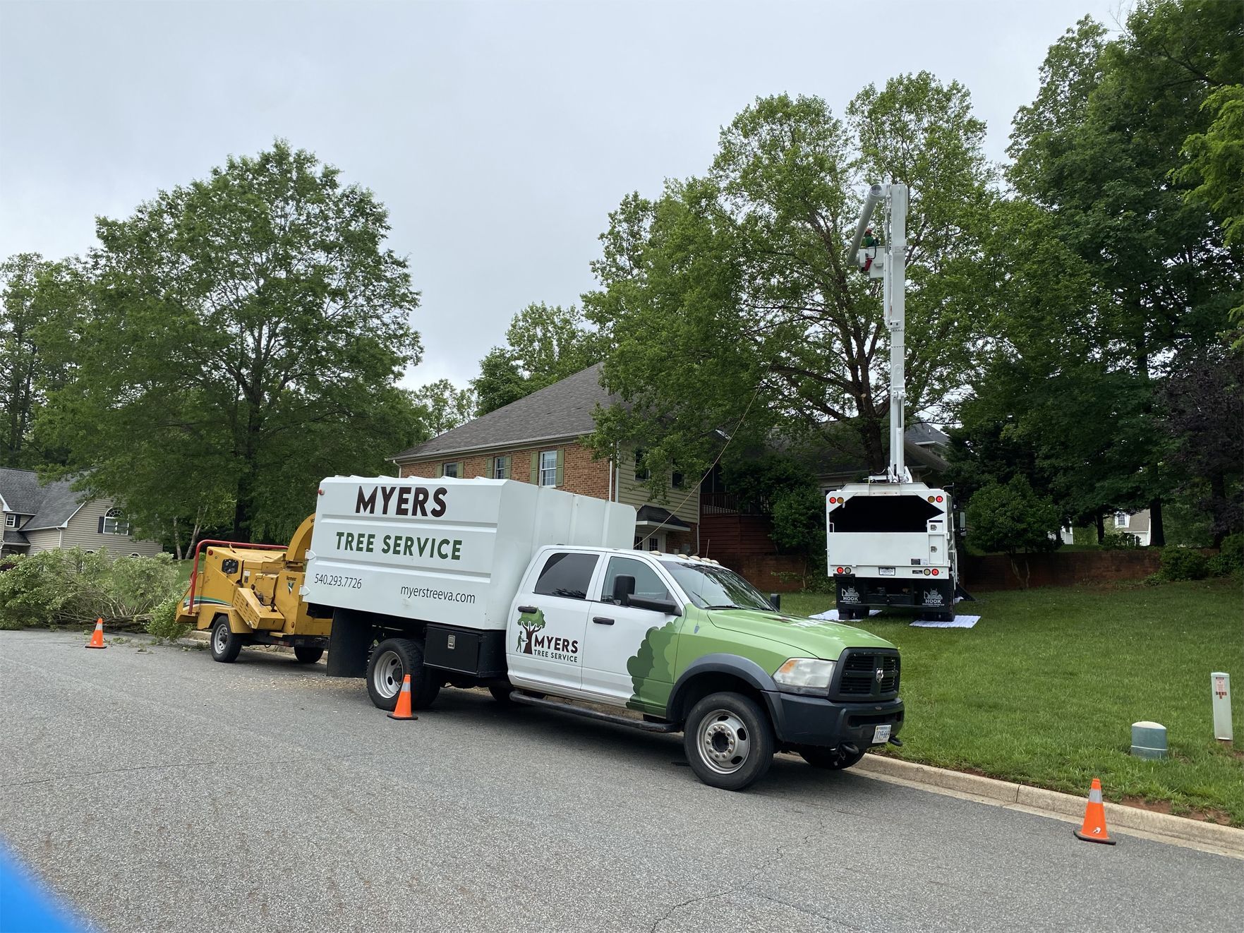 Two trucks are parked on the side of the road in front of a house.