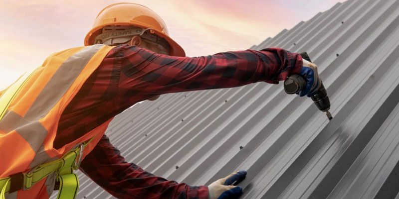 A man is working on a roof with a drill.