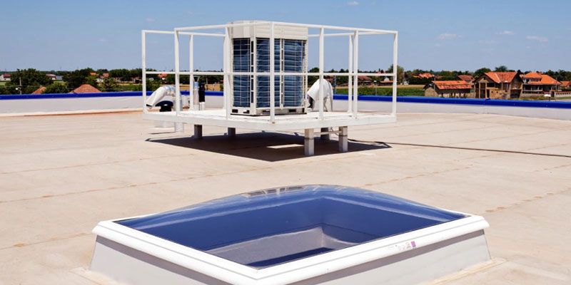 A rooftop with a skylight and a machine on top of it.
