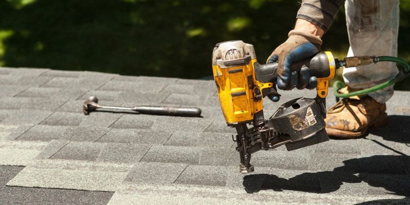 A man is working on a roof with a drill.