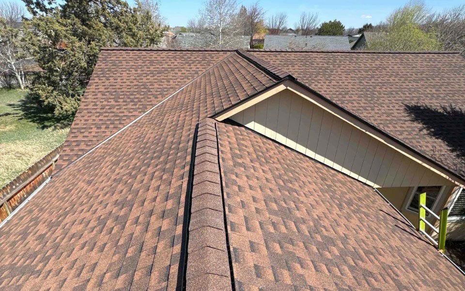 The roof of a house with a brown shingle roof.