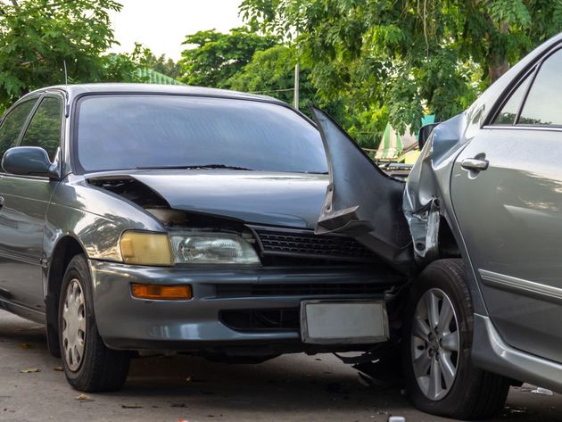 Two cars in a front-end collision on a street, with one car’s hood crumpled.