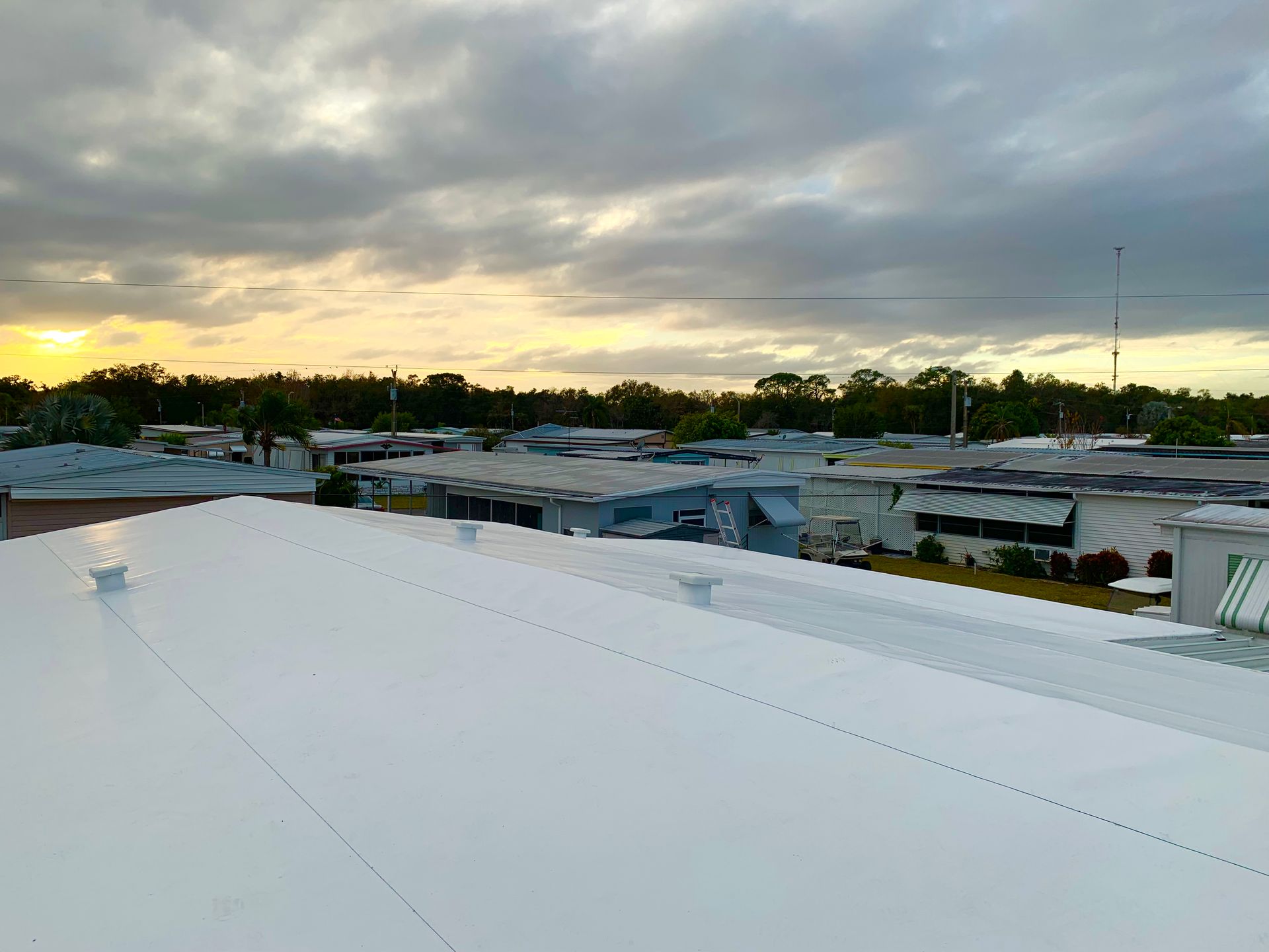 Sunset over a white rooftop and low buildings in a quiet neighborhood