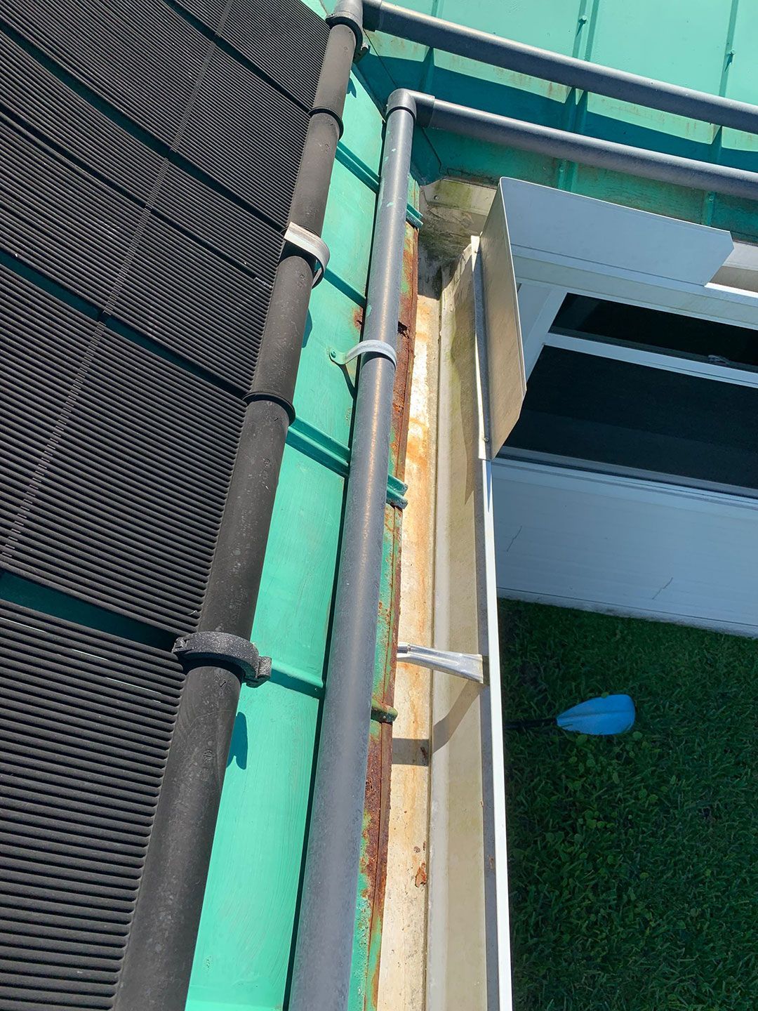 Close-up of a green metal railing beside a black mesh fence and weathered wooden beam.