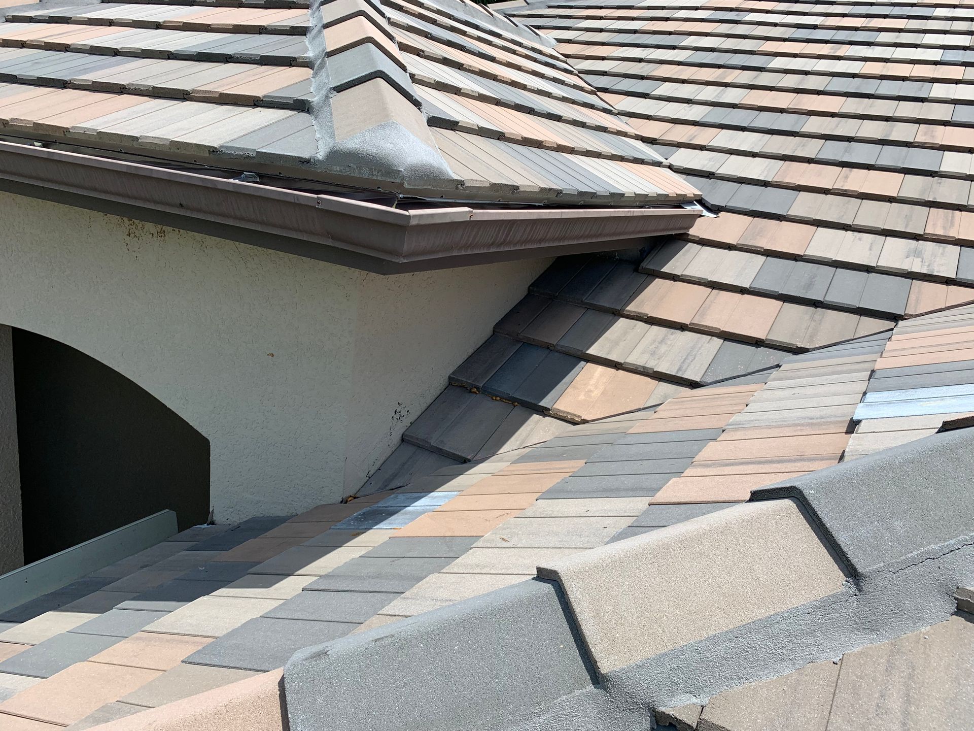 Close-up of a sloped shingle roof with a dormer and gray ridge caps
