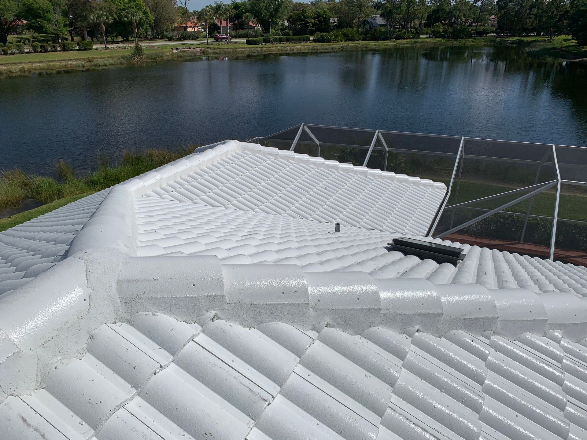 White inflatable roof structure beside a lake, with trees and a wire fence in the background