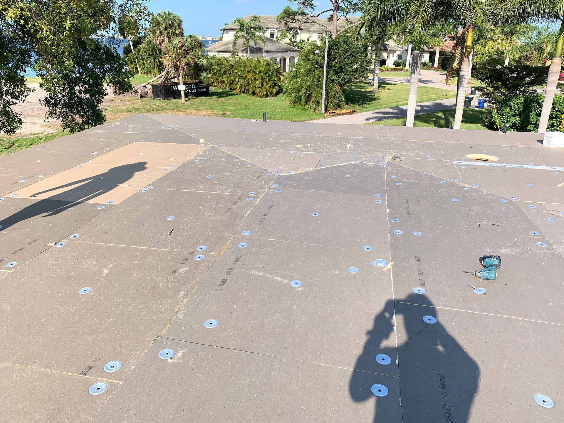 Rooftop with scattered tools and blue markers, overlooking trees and a building in the distance.