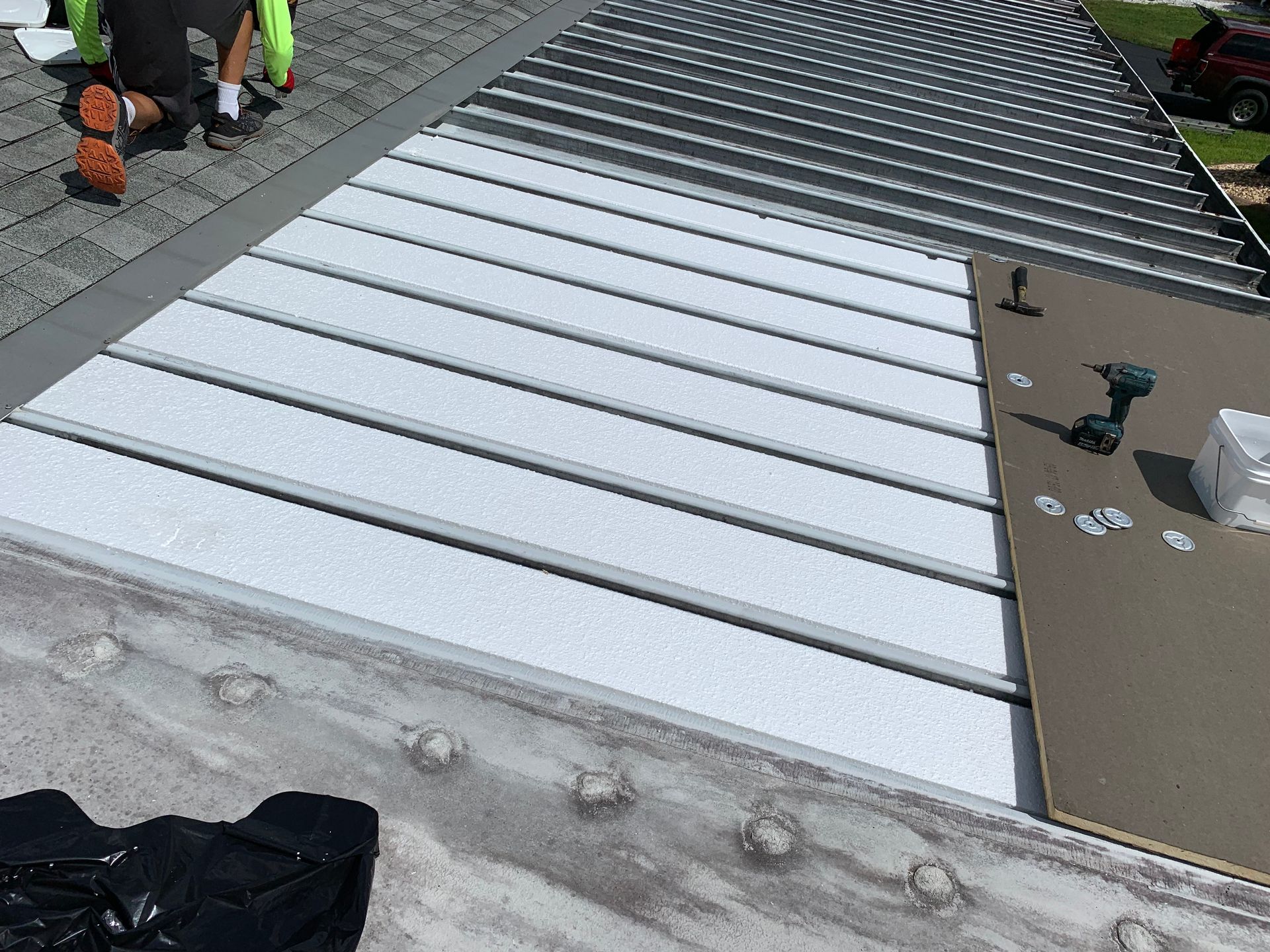 Workers installing a silver metal ramp or walkway outdoors next to a conveyor or platform