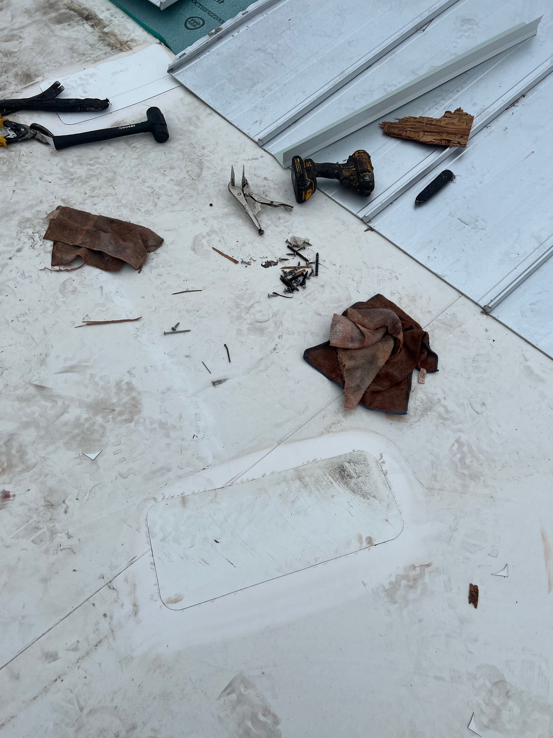 Scattered screws, leaves, and debris on a white rooftop or deck surface