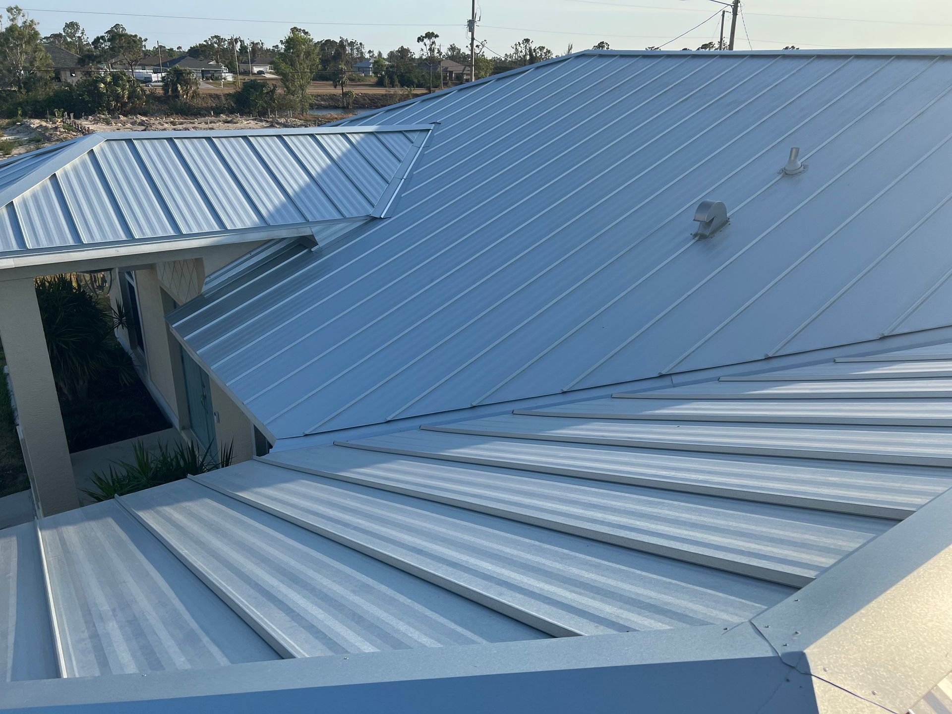 Blue corrugated metal roof with a large open skylight and surrounding trees in the background