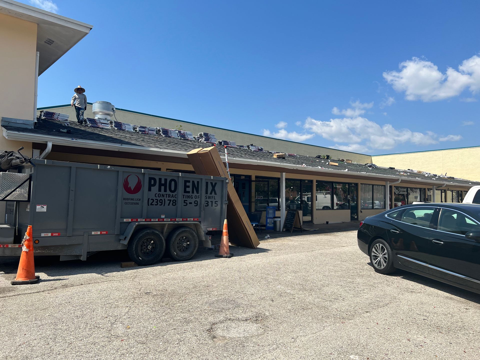 Food truck beside a strip mall in a parking lot, with a car and traffic cone nearby.