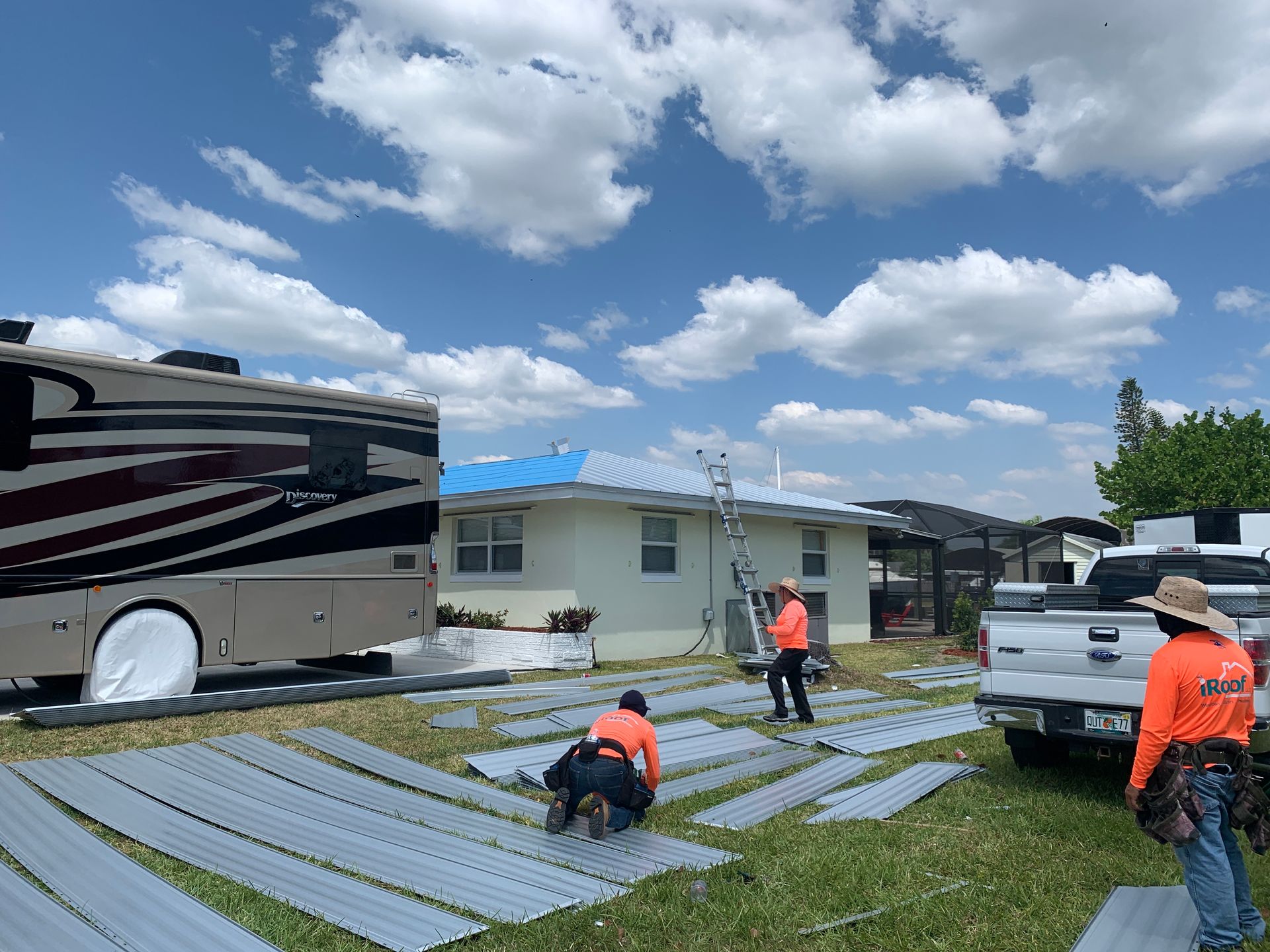 Workers installing solar panels on a residential roof under a partly cloudy sky