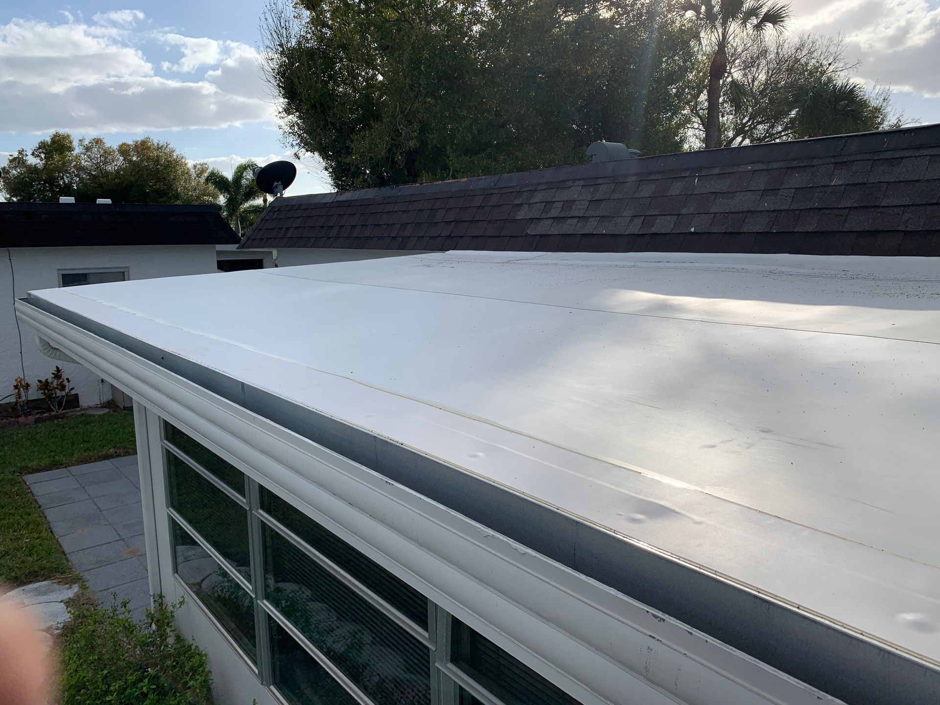 White roof on a house with skylights, viewed from above in a backyard setting