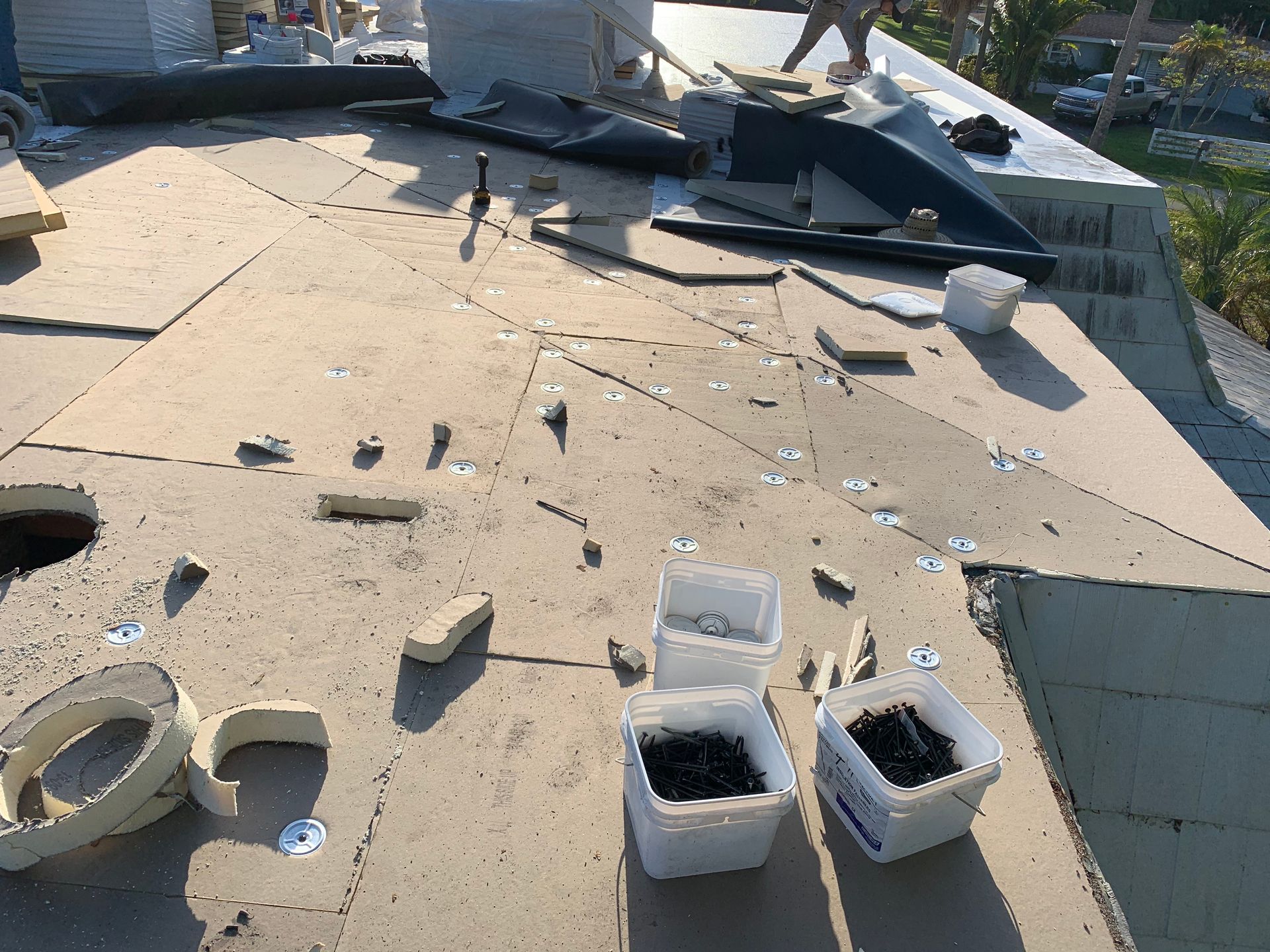 Flat rooftop with scattered debris, vent pipes, and buckets after apparent storm damage