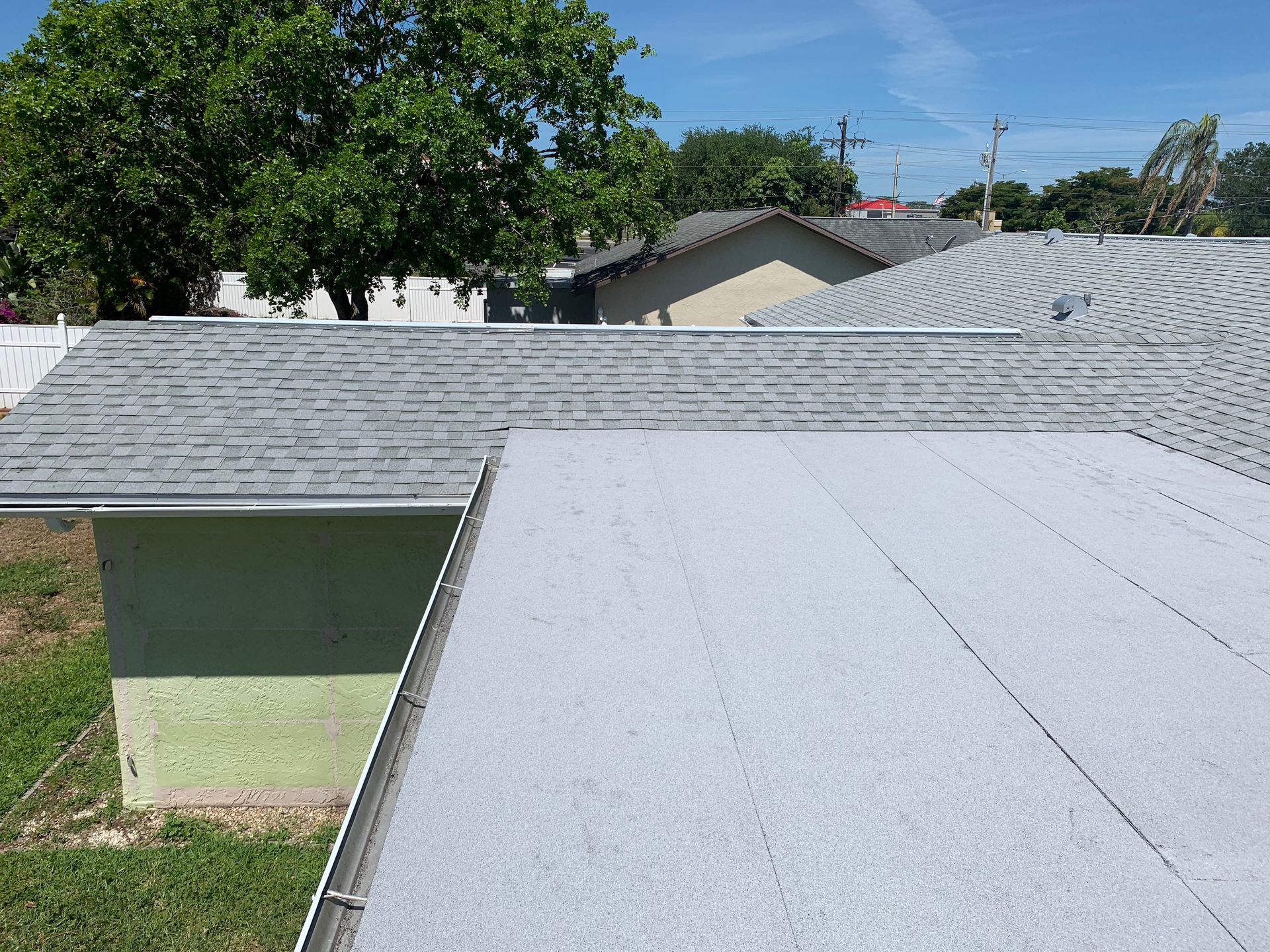 Residential roofs with gray shingles and trees in the background