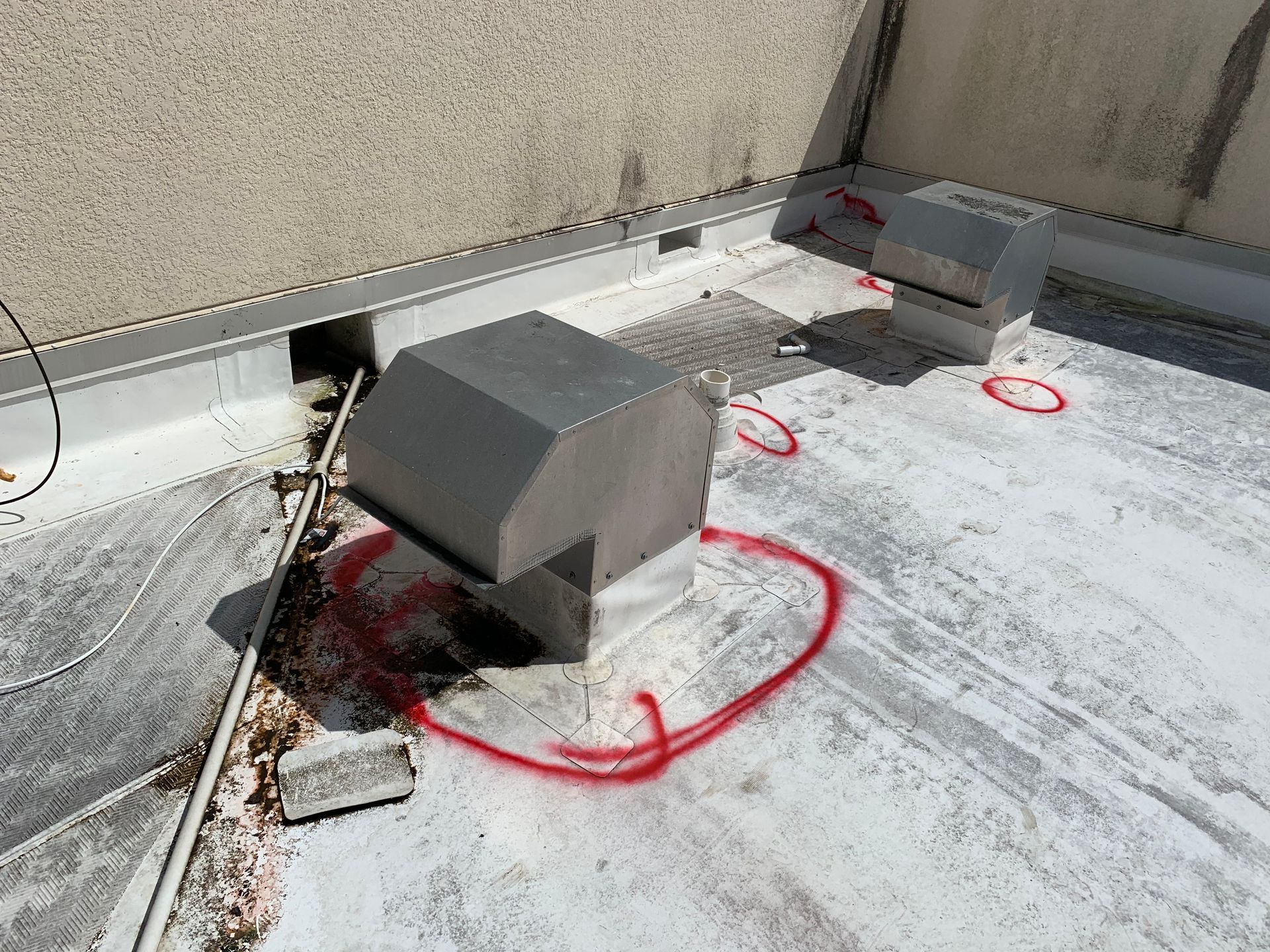 Rooftop HVAC unit with red inspection markings and a damaged, dark-stained base nearby