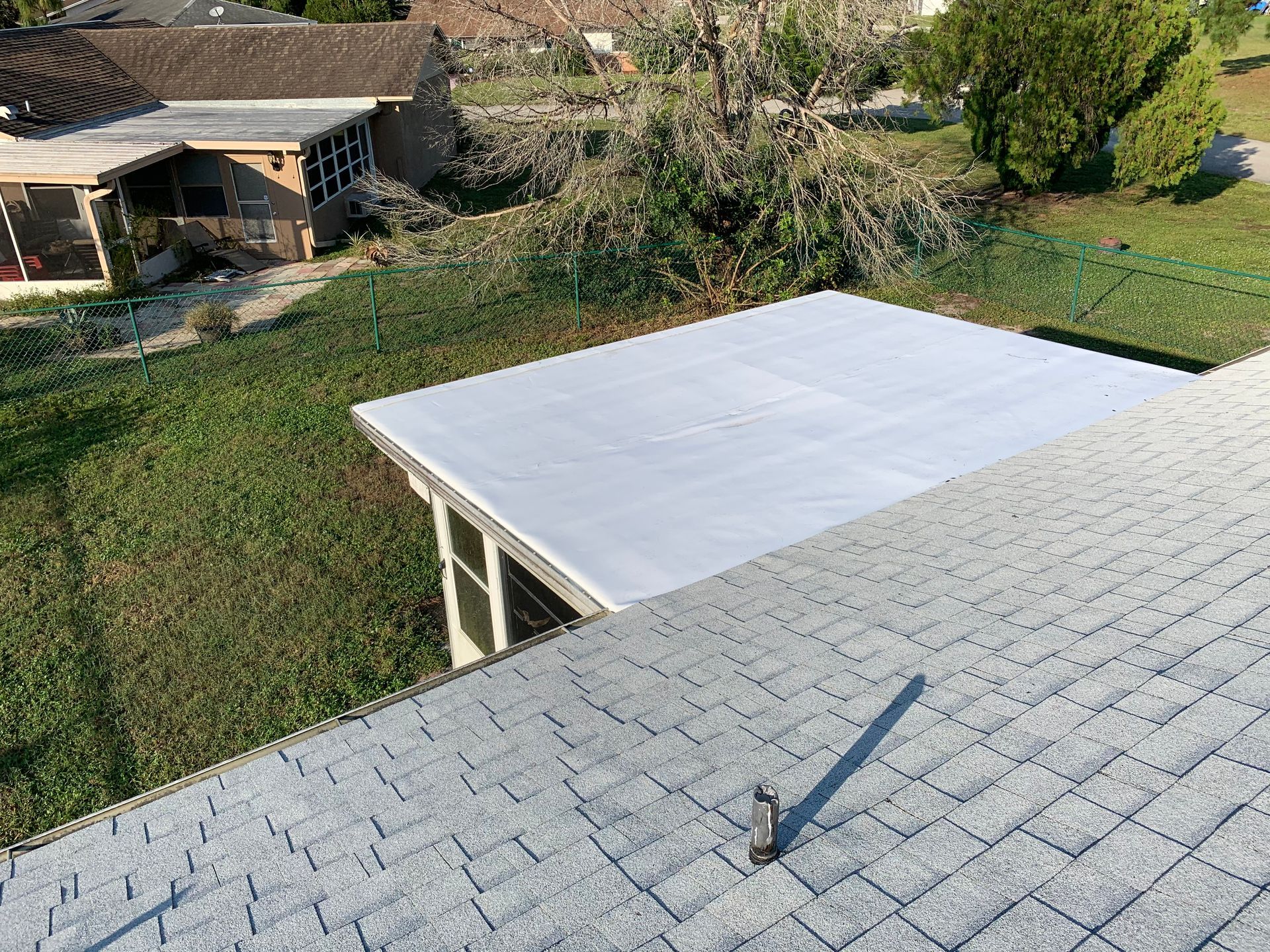 Backyard with a white-roofed patio and a gray shingle roof in the foreground