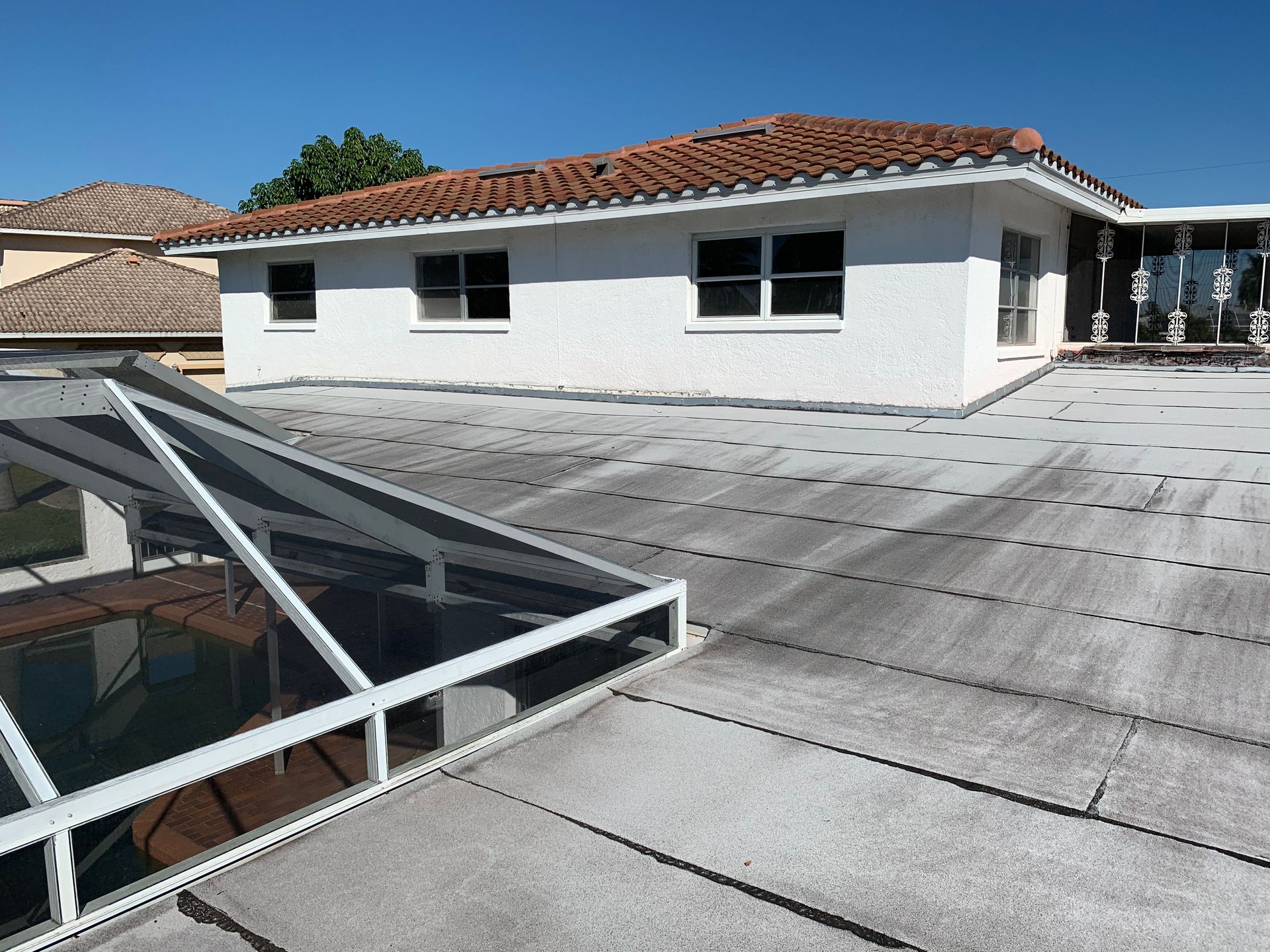 Rooftop with white building, red tile roof, and skylight under a clear blue sky