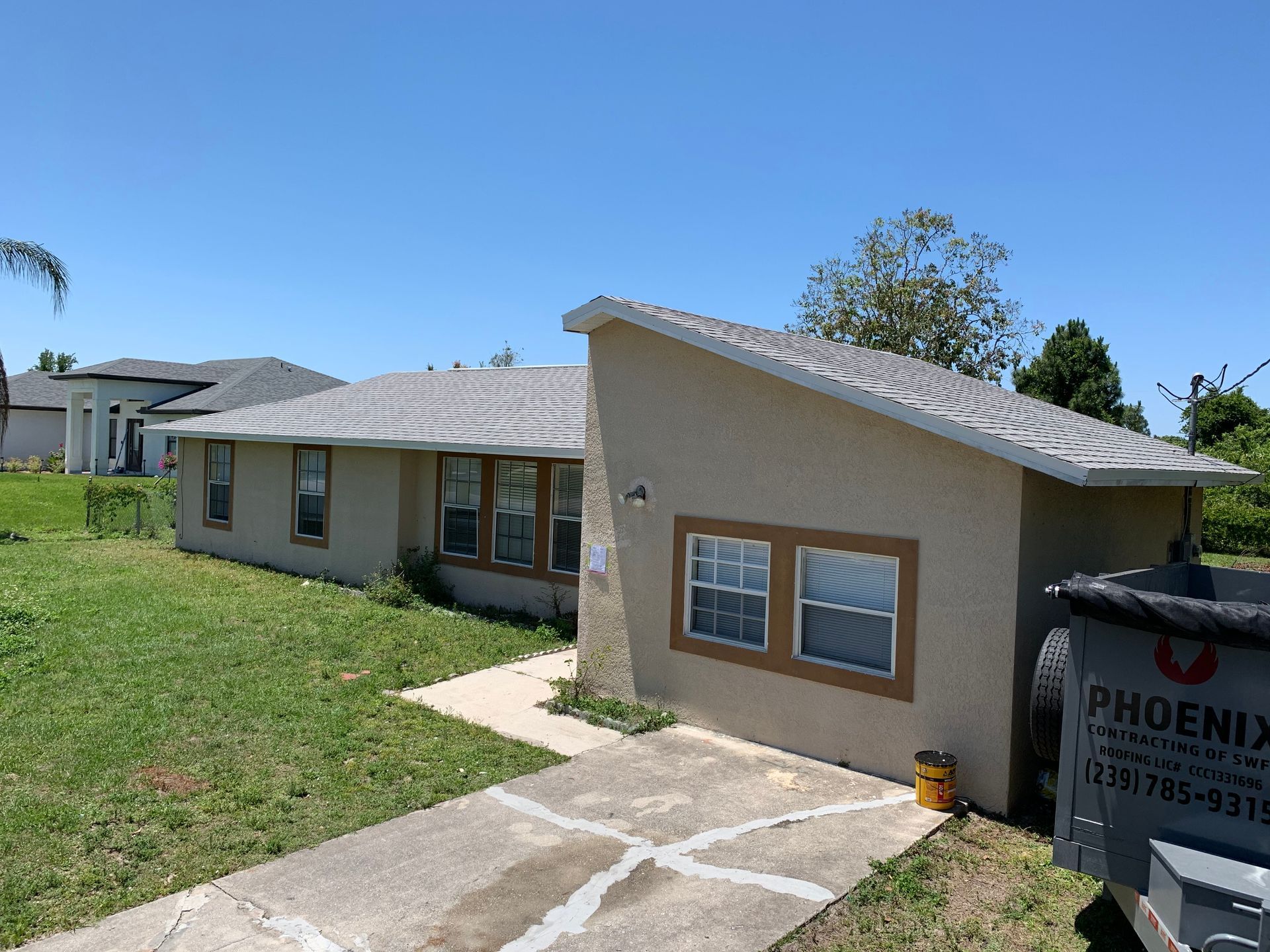 Single-story beige house with a driveway, front lawn, and a Phoenix sign in the yard