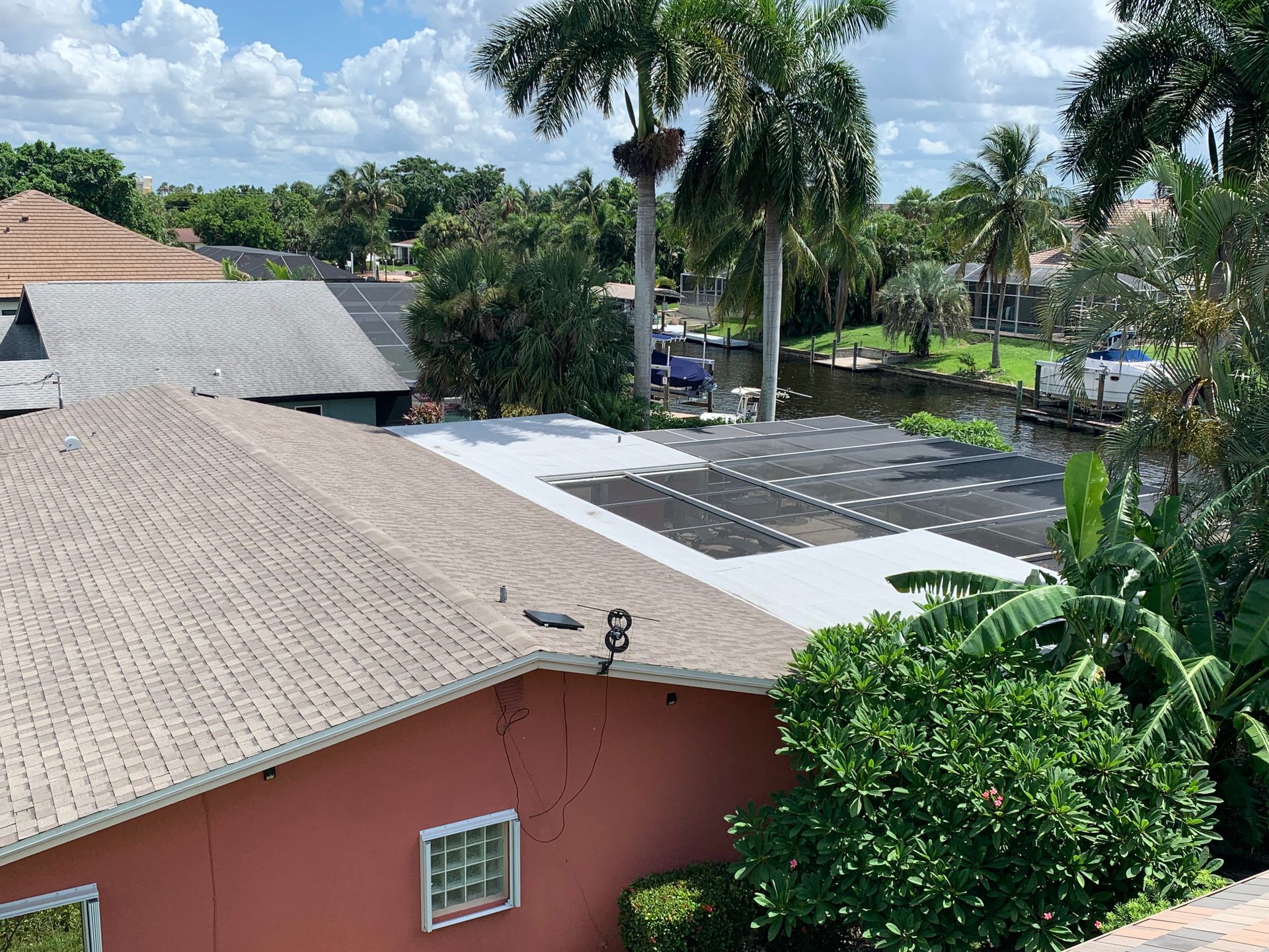 Rooftops and palm trees in a sunny residential area under a cloudy sky