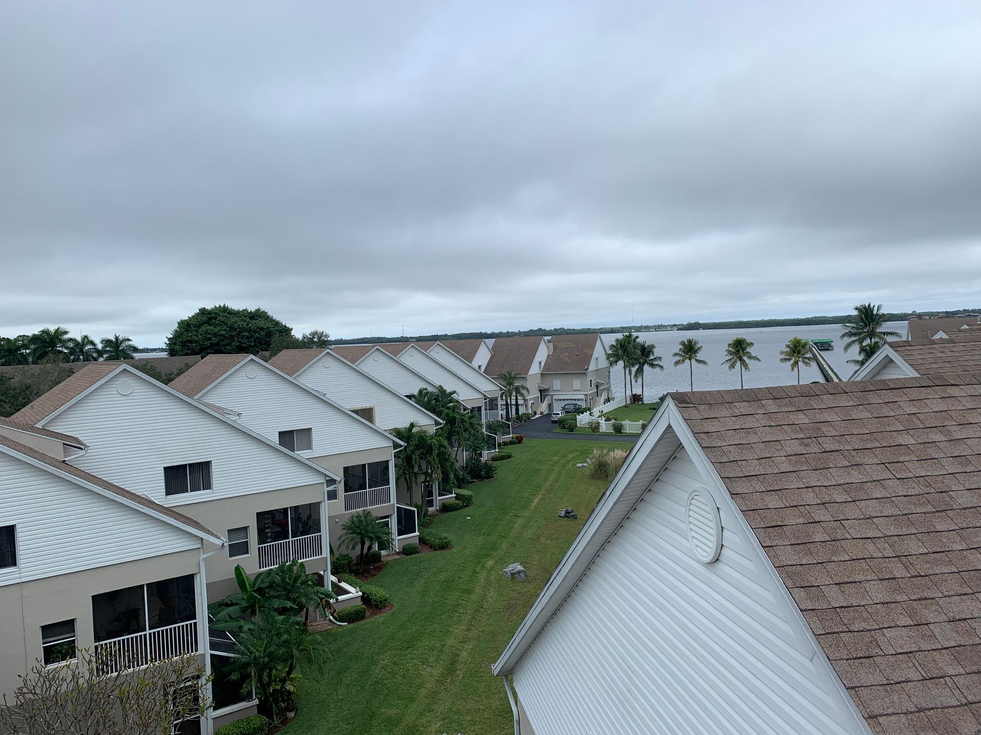 Rows of white-roofed houses on a grassy hillside under a cloudy sky