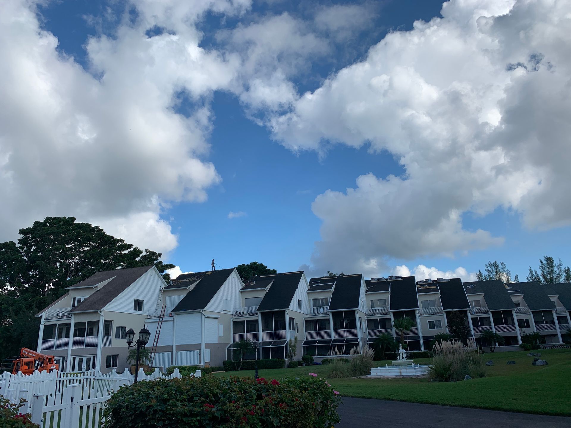 Row of white houses on a green hill beneath a cloudy blue sky