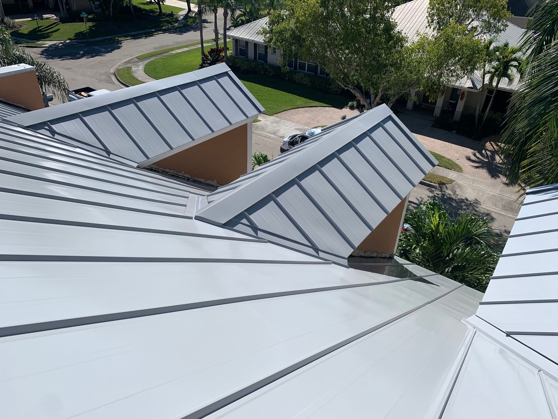 White metal rooftops above a courtyard and trees, seen from above